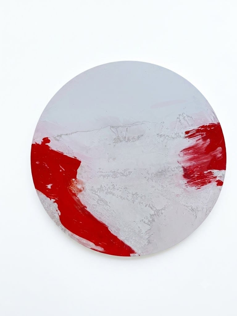 A minimalist abstract painting featuring bold red brushstrokes on a textured white circular canvas.