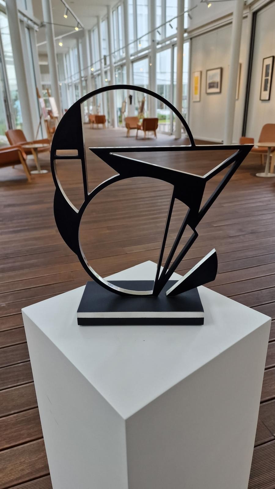 A black and white sculpture on a wooden base.