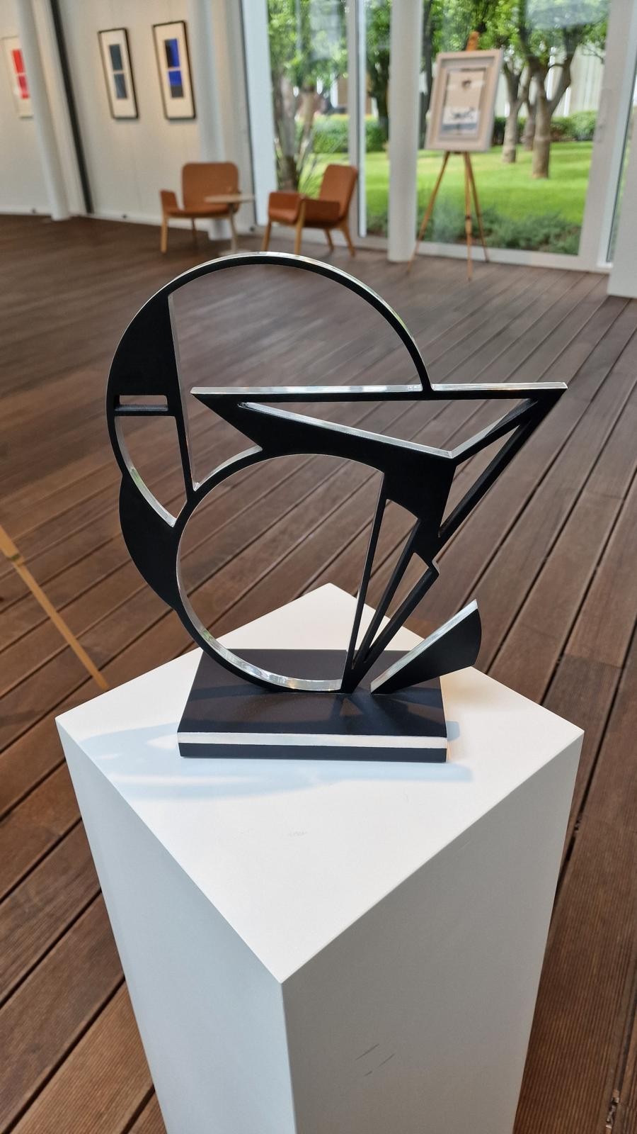 A black and white sculpture on a wooden base.