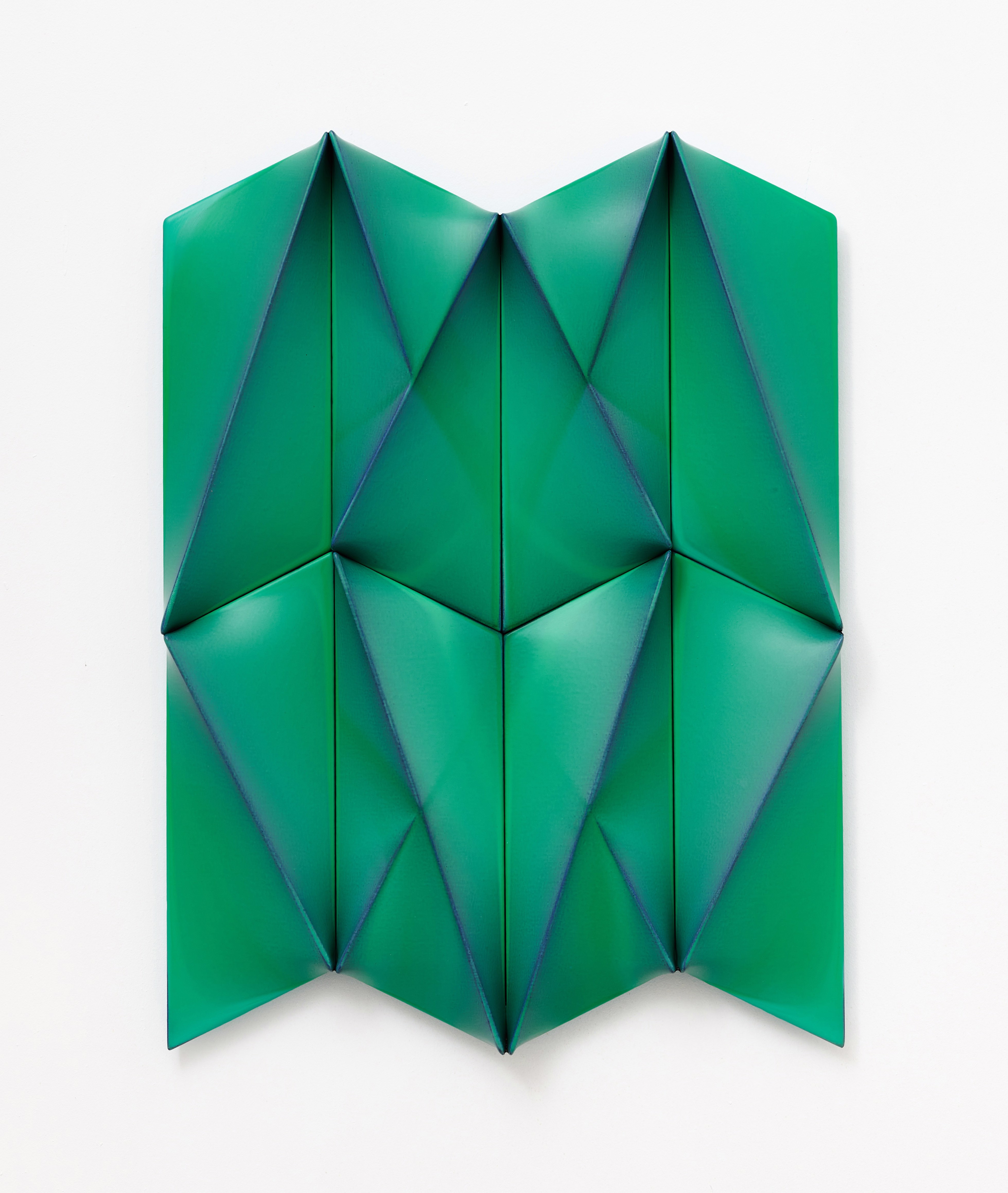 A green origami piece on a white surface.