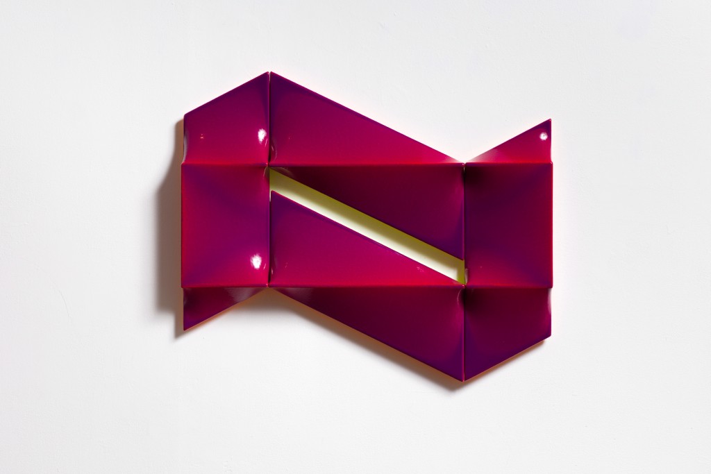 A pink origami fish on a white surface.