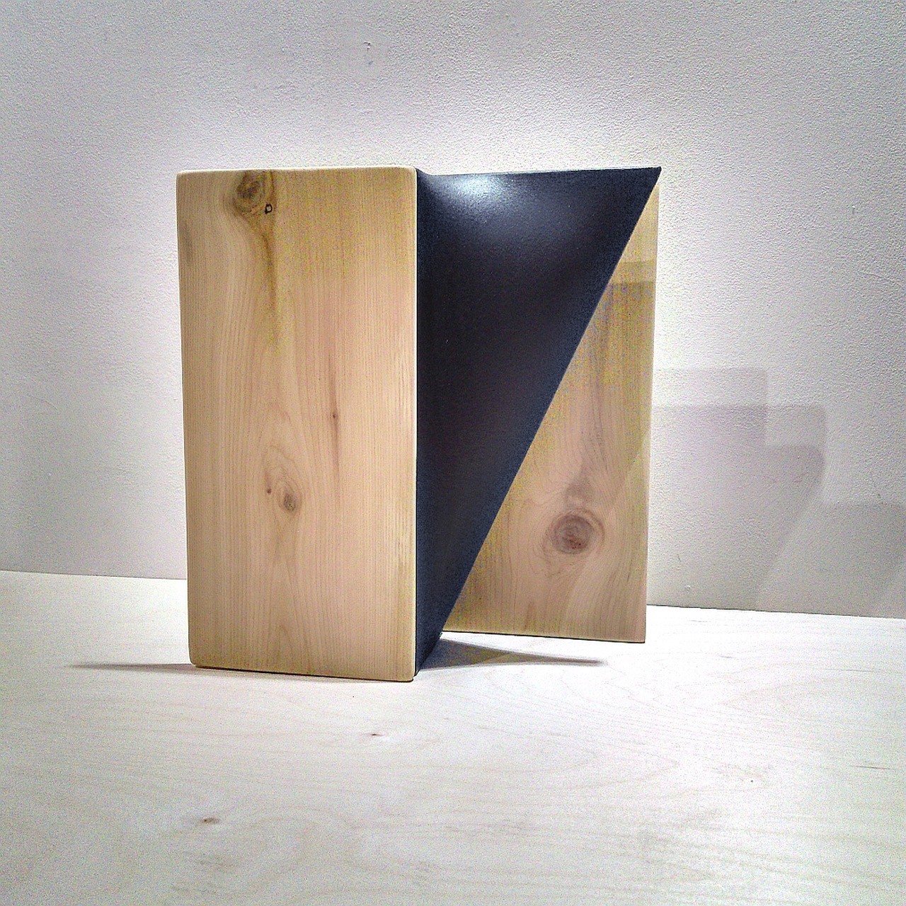 A wooden block with a black triangle on top of it.