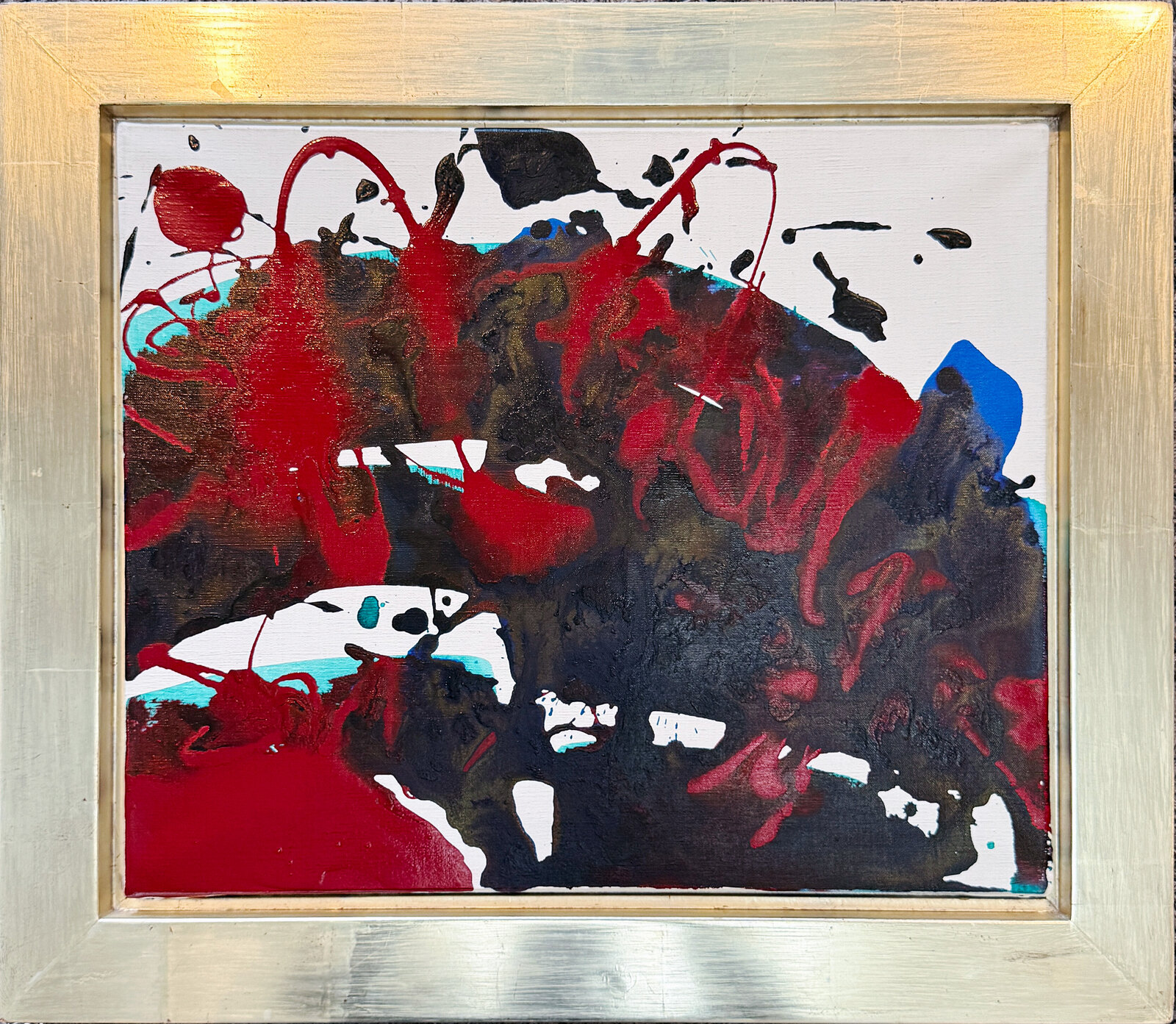 An abstract composition featuring bold red and black splatters against a white background, framed in metallic silver.