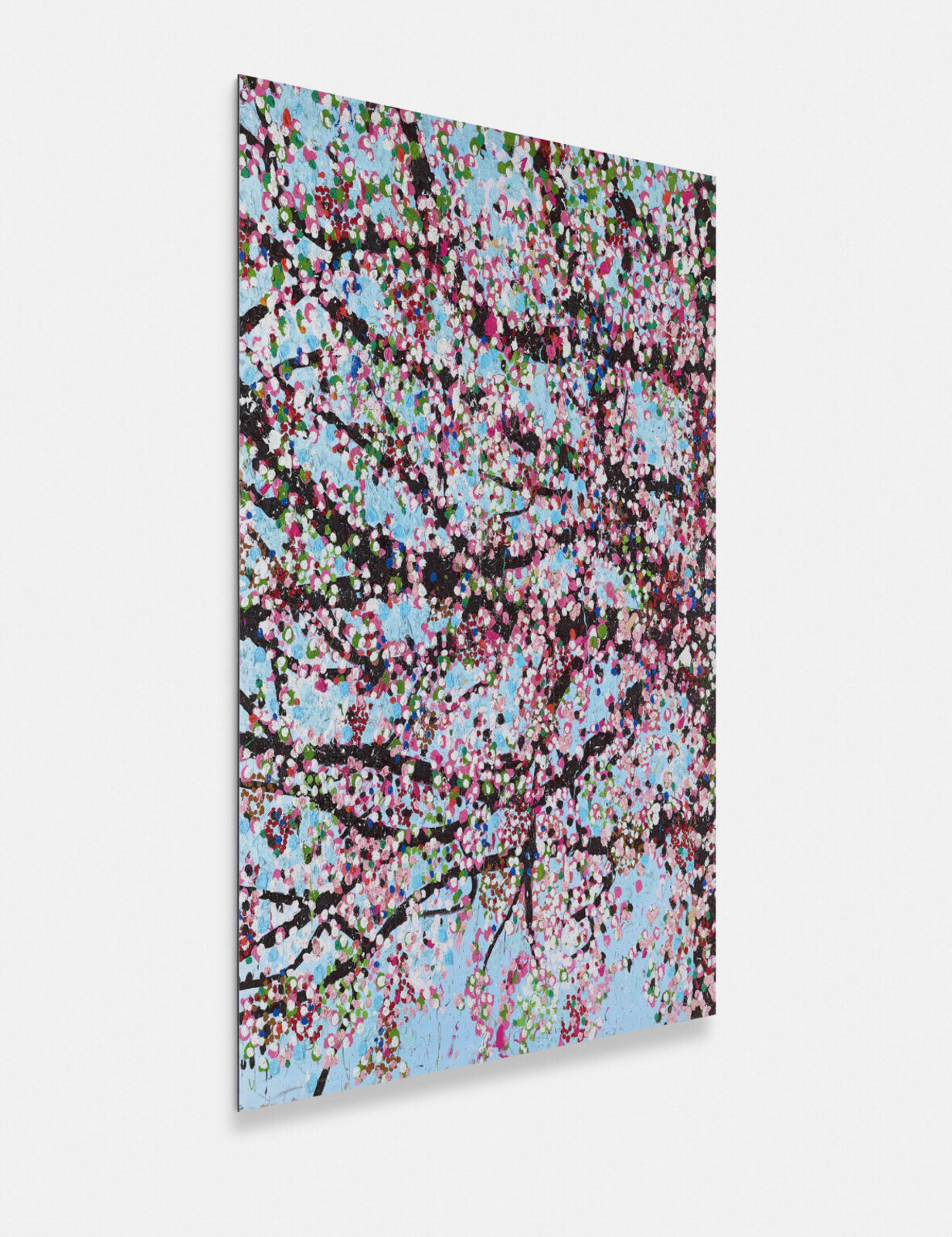 A dense, colorful tree in full bloom against a light blue sky.