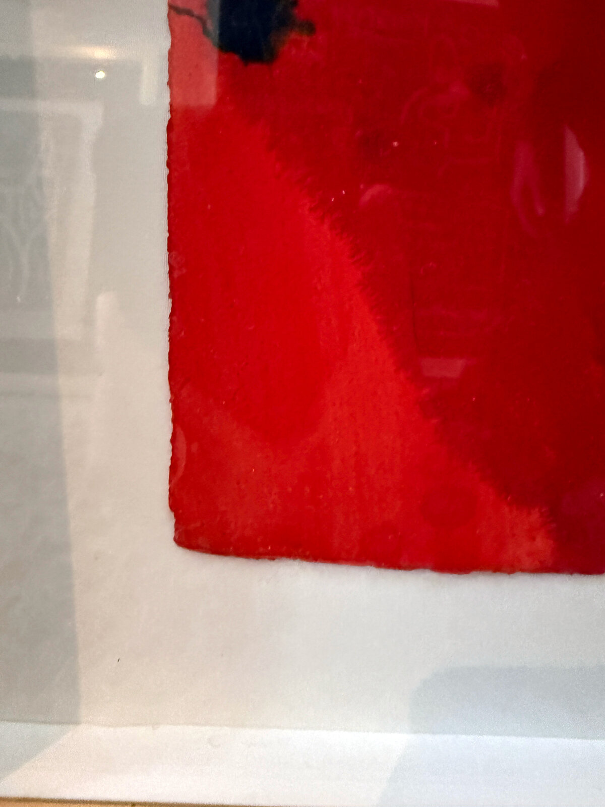 A framed abstract piece featuring bold red and black shapes against a white background with splattered ink.