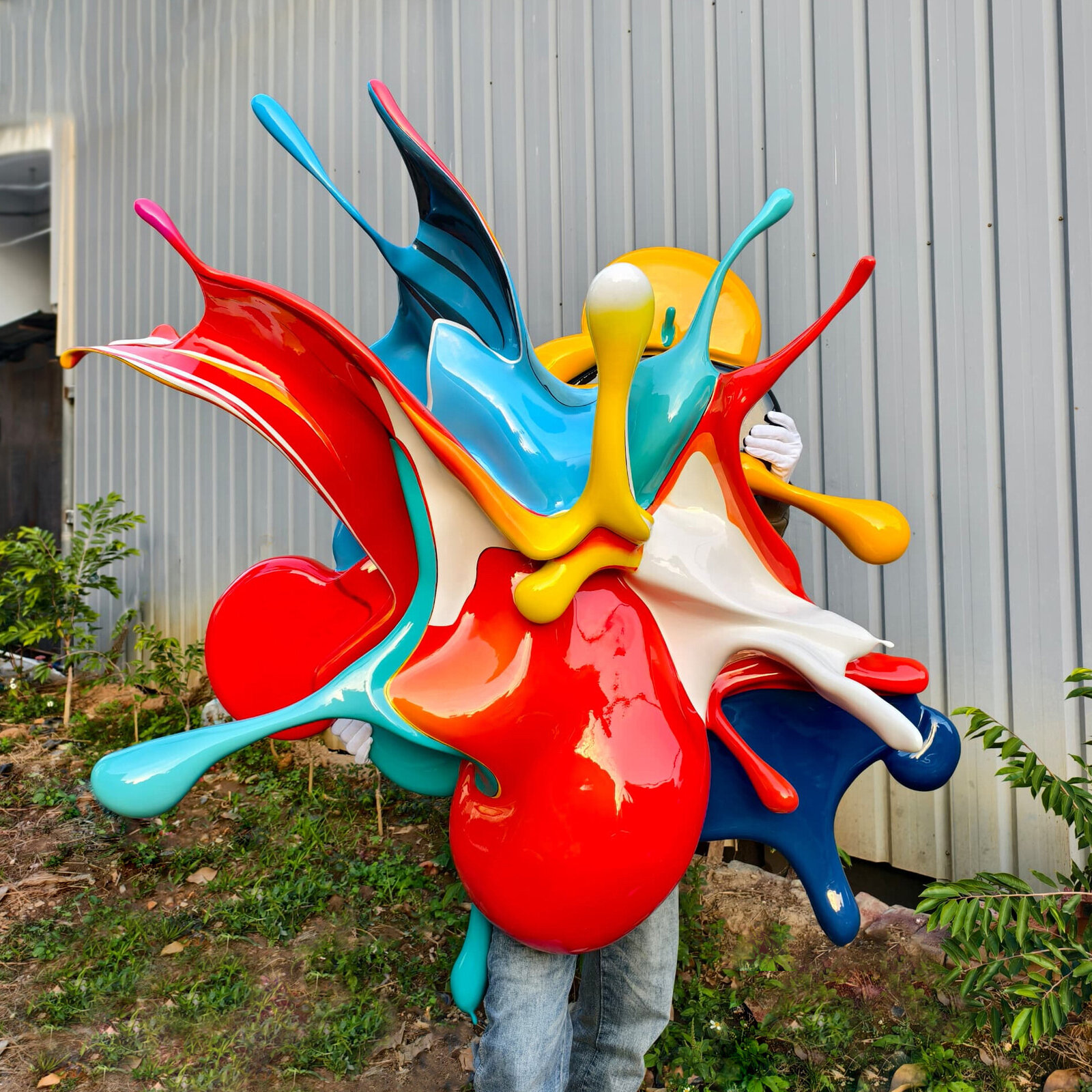 A dynamic, glossy sculpture of colorful paint splashes frozen in mid-air against a plain background.