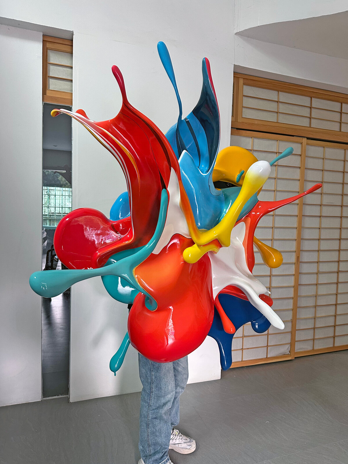 A dynamic, glossy sculpture of colorful paint splashes frozen in mid-air against a plain background.