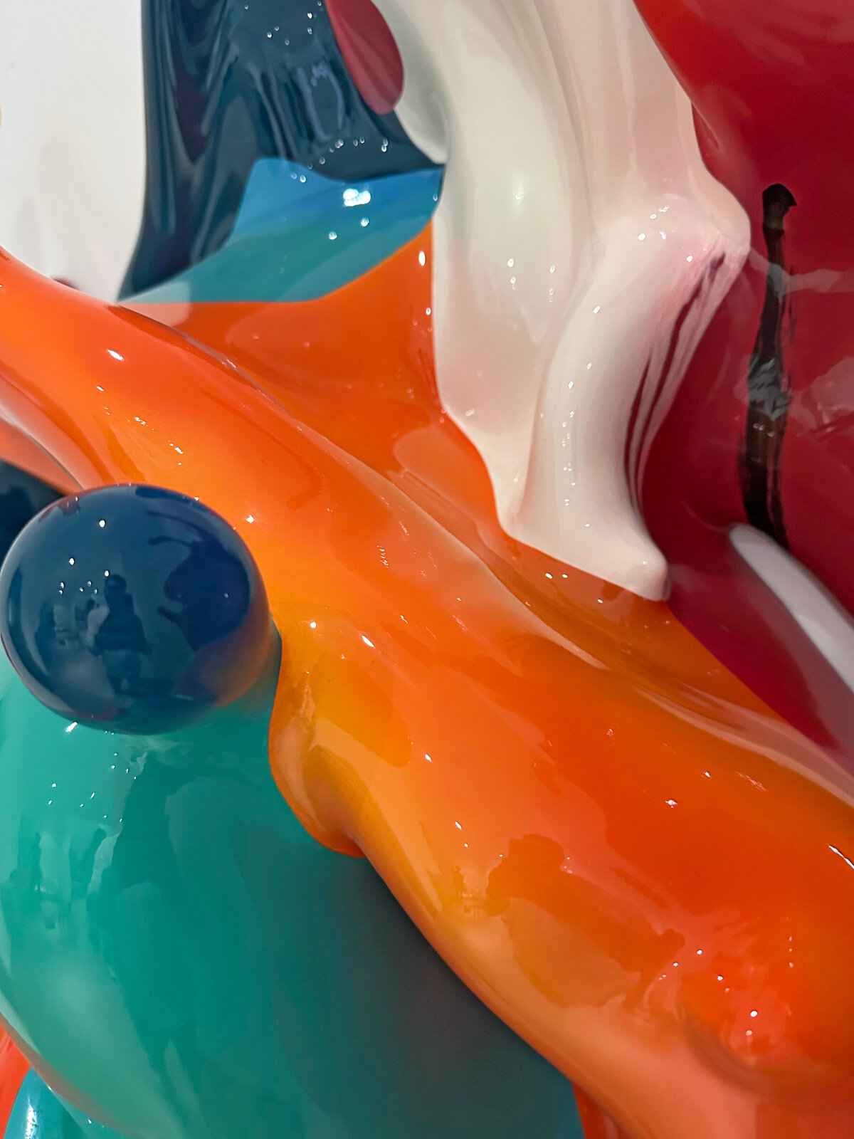 A dynamic sculpture of glossy, multi-colored paint splashes frozen in motion against a plain white background.