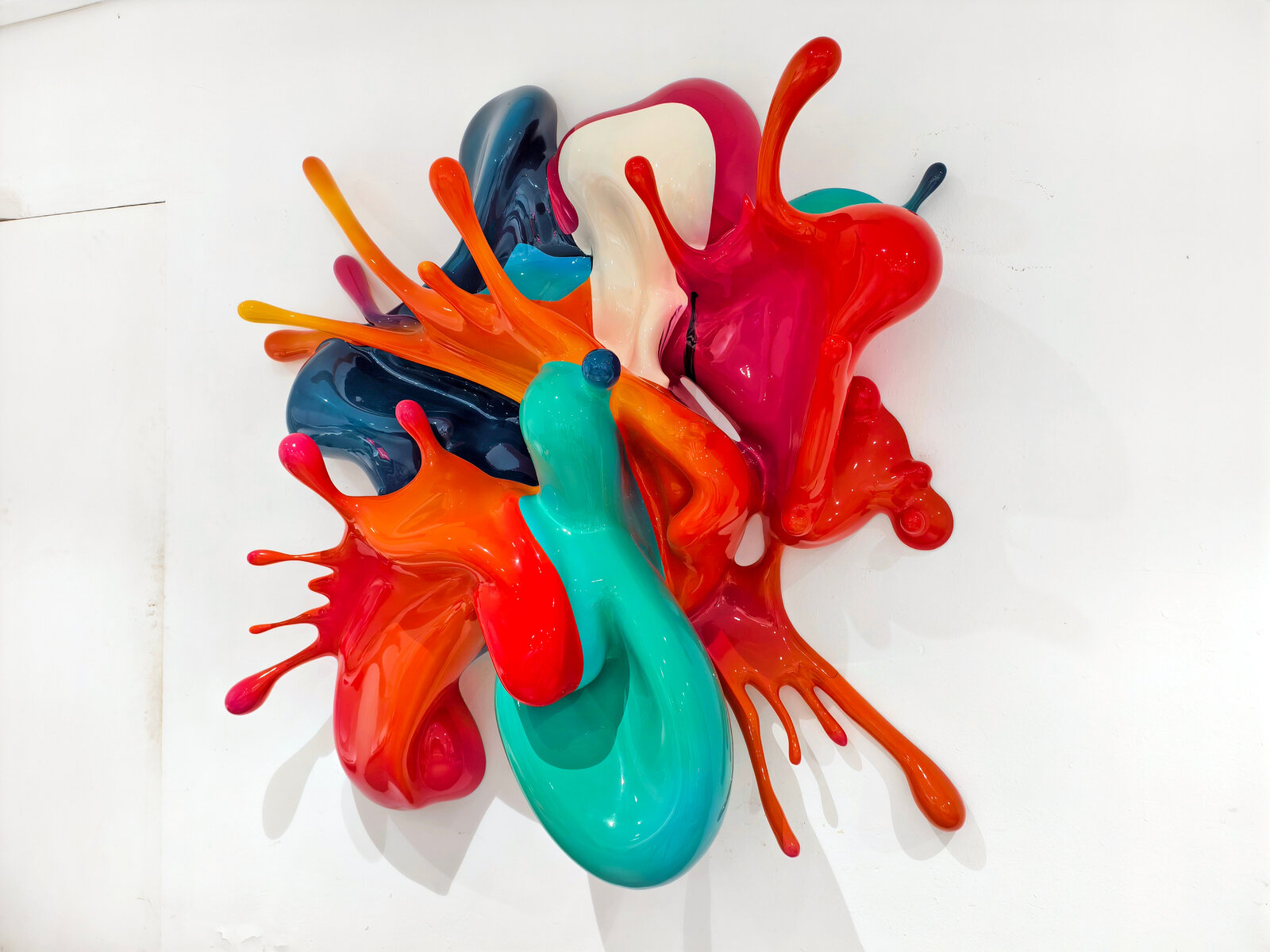 A dynamic sculpture of glossy, multi-colored paint splashes frozen in motion against a plain white background.