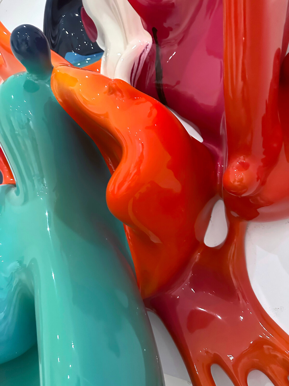A dynamic sculpture of glossy, multi-colored paint splashes frozen in motion against a plain white background.