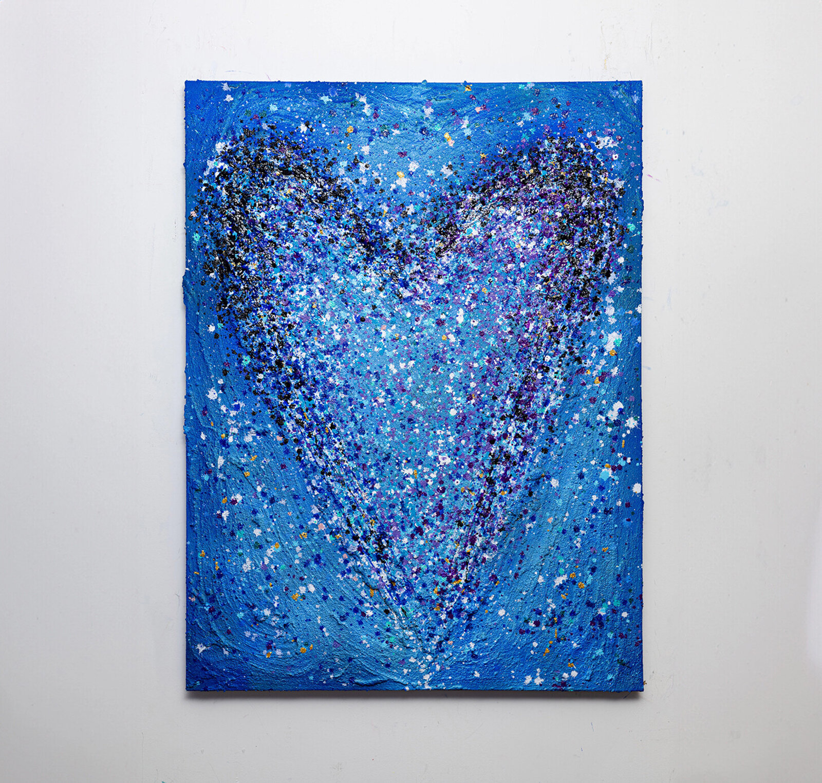 A textured abstract composition featuring a heart shape formed by splattered paint.