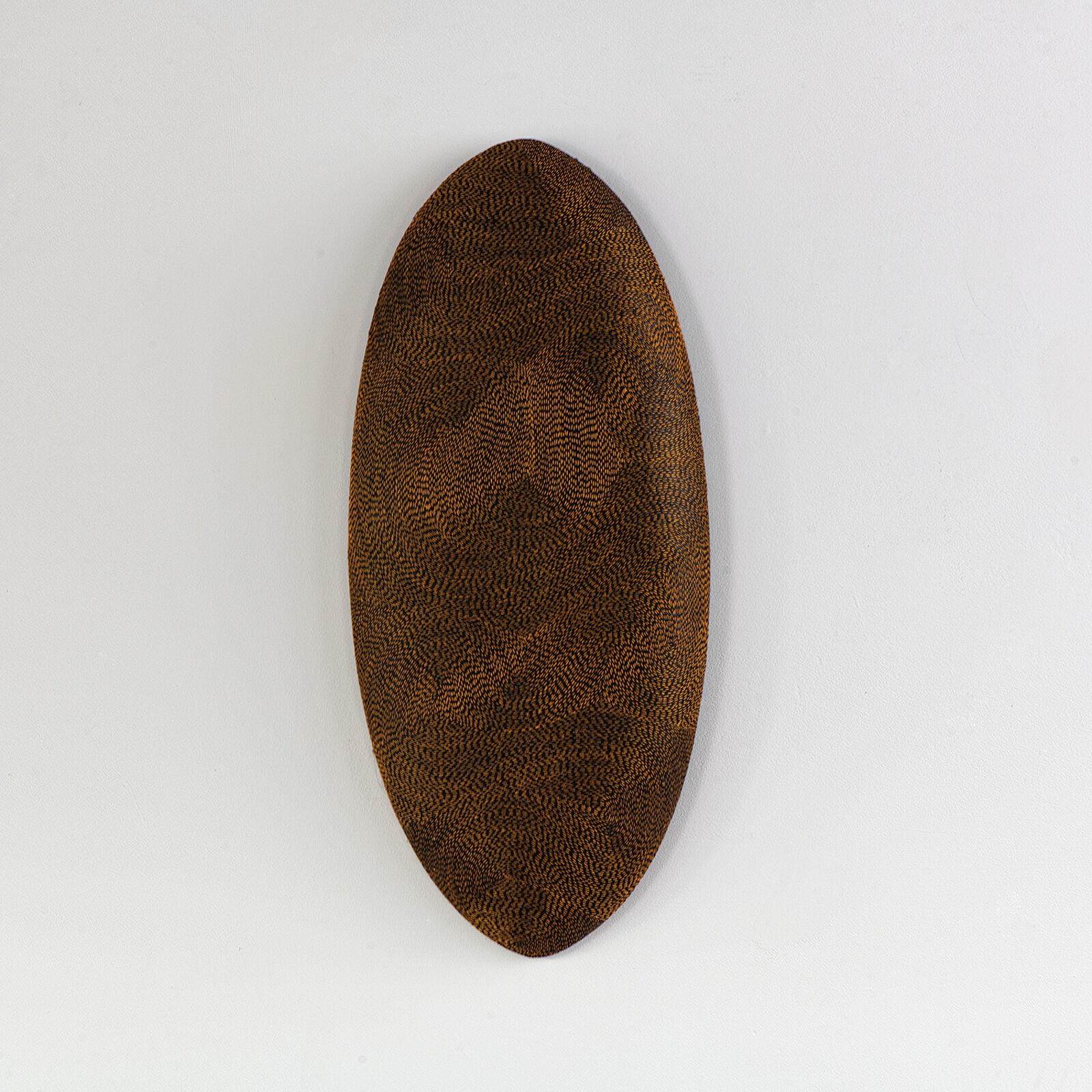 A minimalist composition featuring a textured, dark brown oval object against a stark white background.