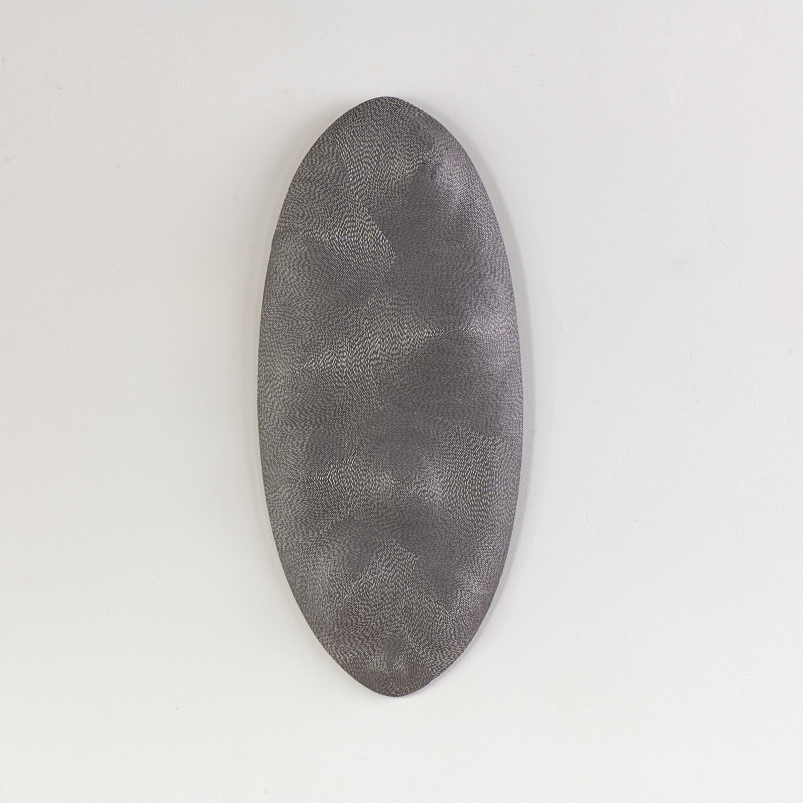 A minimalist grey oval with a fine, textured surface against a plain white background.