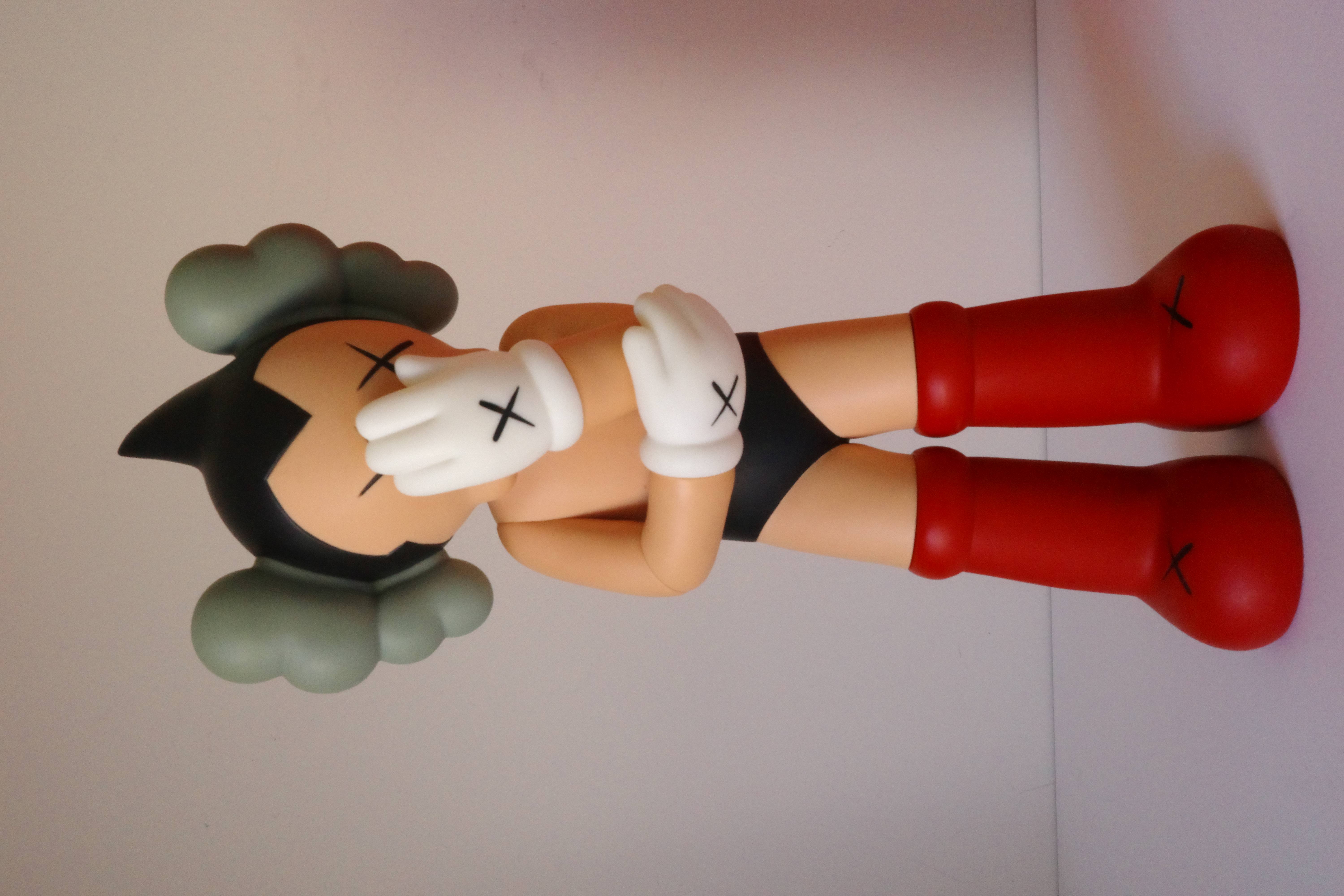 A figurine of a woman laying on the ground with her head in her hands.