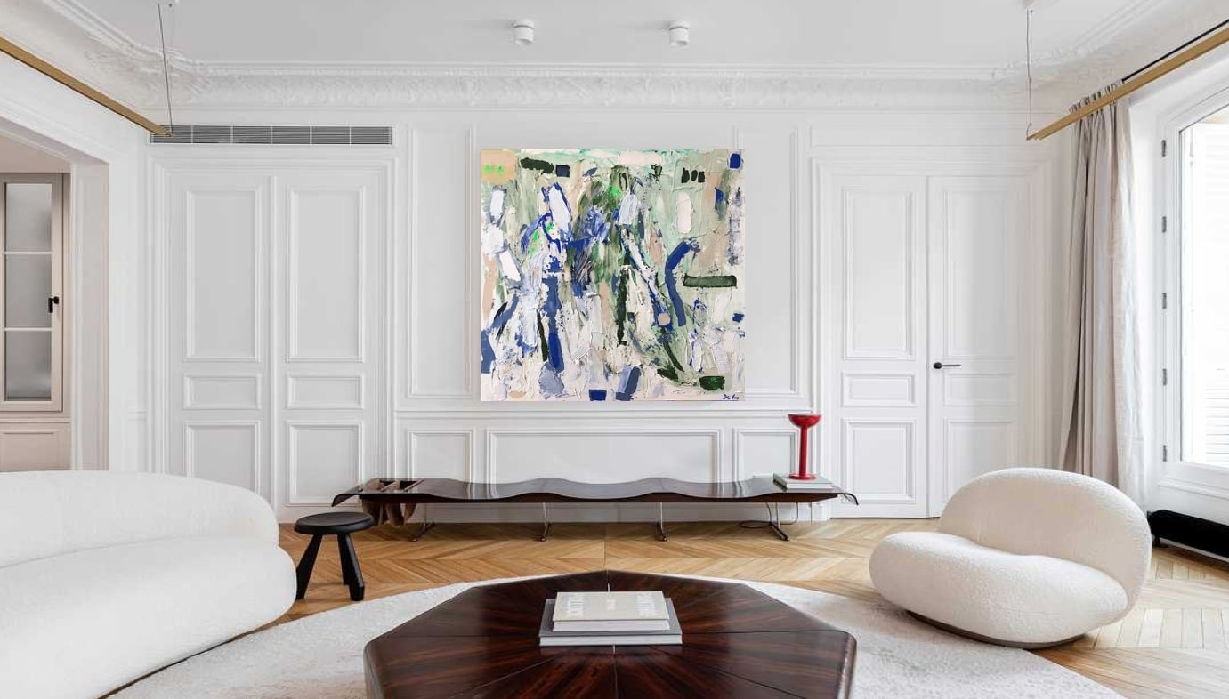 A living room with a white couch and a painting on the wall.