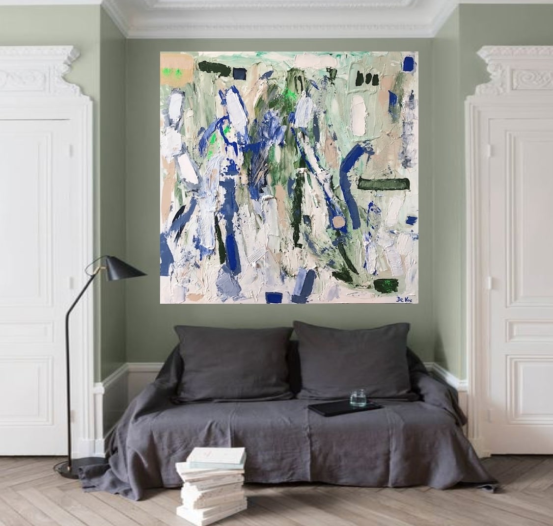 A living room with a white couch and a painting on the wall.