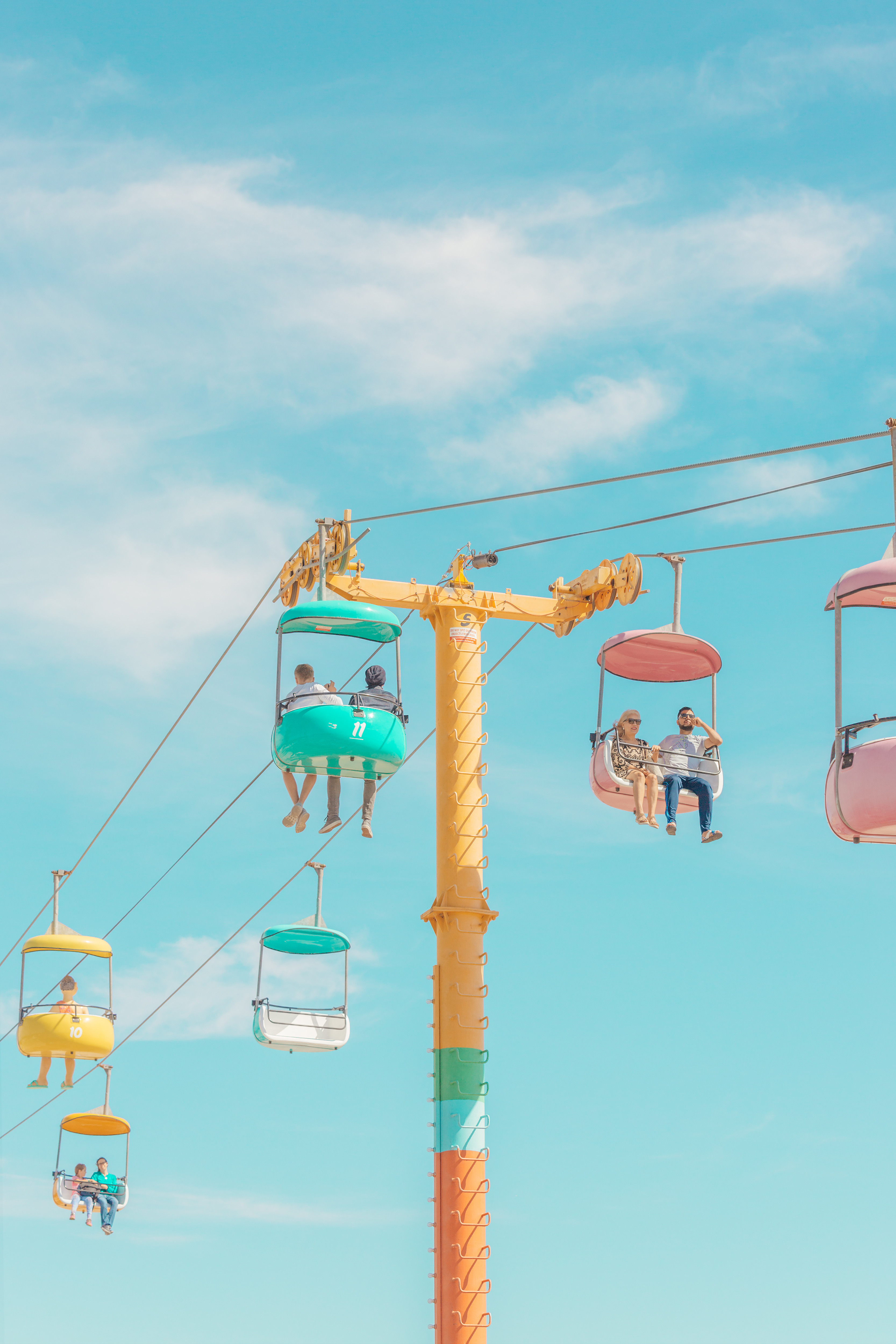 A group of people riding on a cable car at an amusement park.