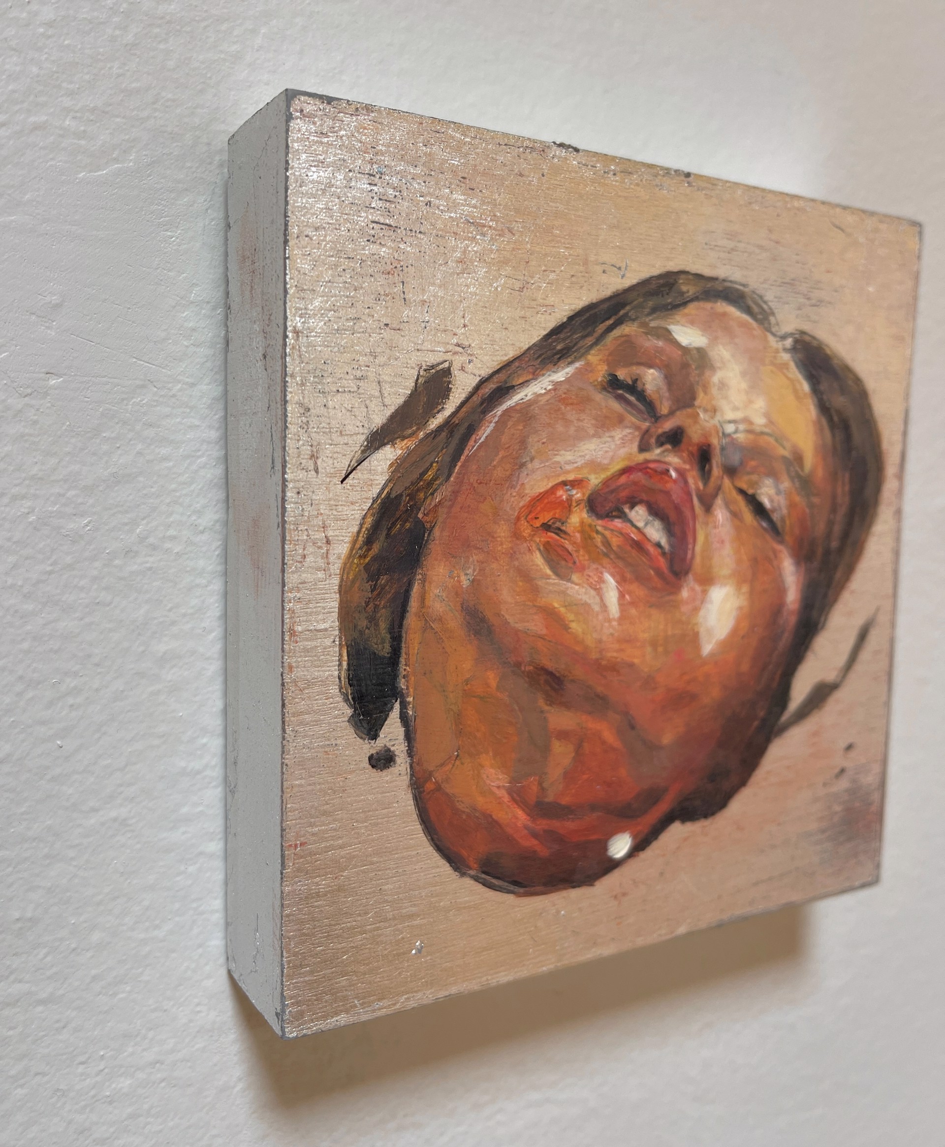 A painting of a woman's face on a wooden surface.