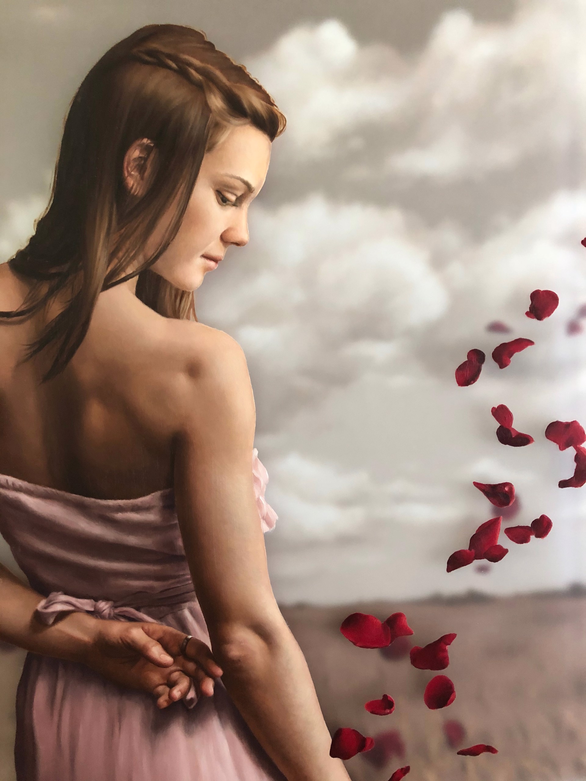 A woman in a pink dress standing in a field of rose petals.