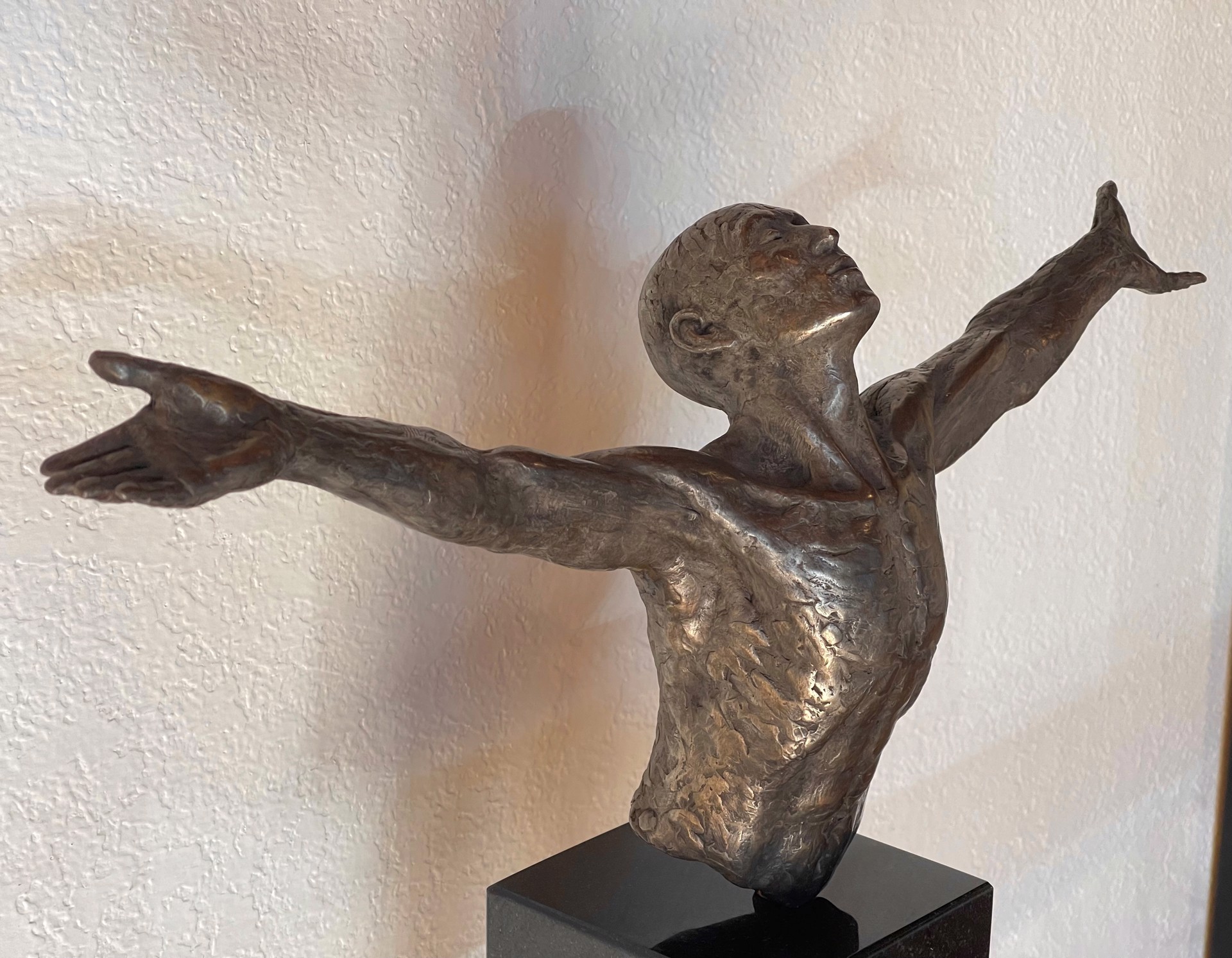 A bronze sculpture of a man with his arms outstretched.