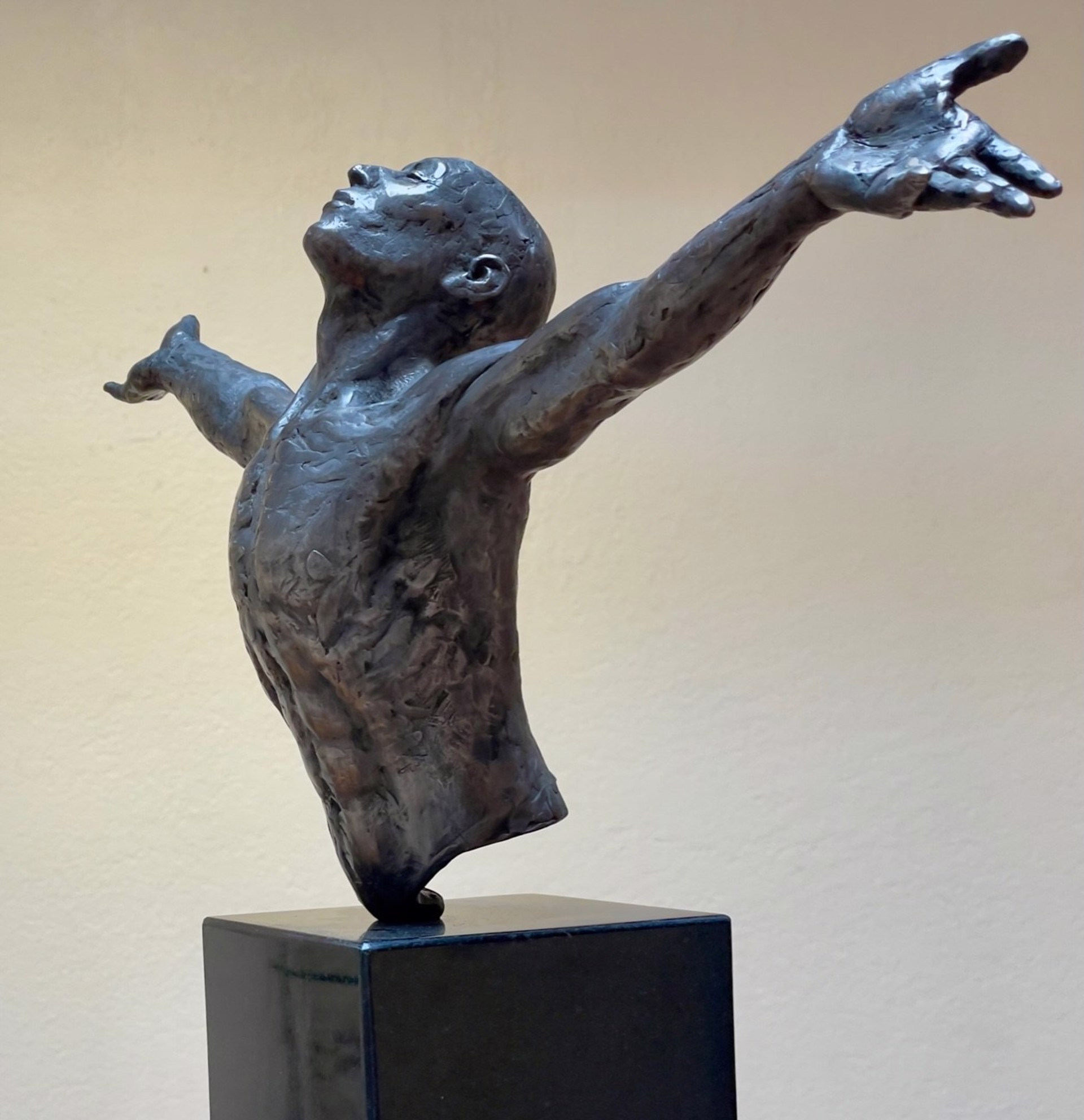 A bronze sculpture of a man with his arms outstretched.