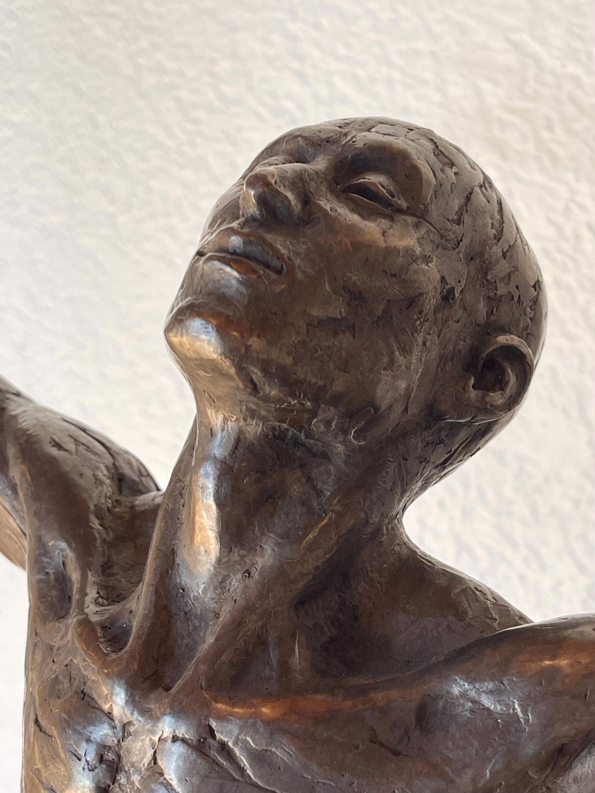 A bronze sculpture of a man with his arms outstretched.