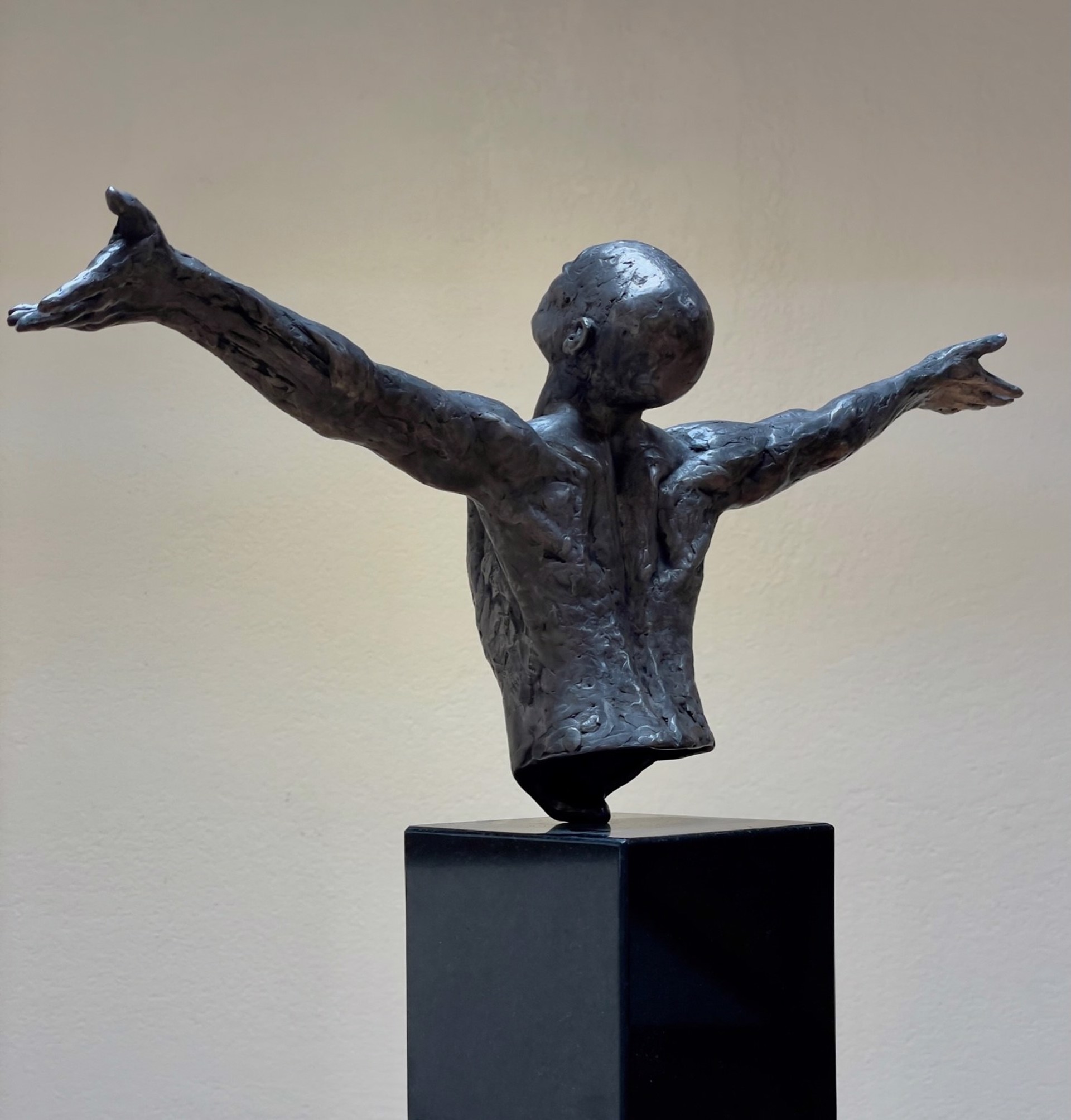 A bronze sculpture of a man with his arms outstretched.