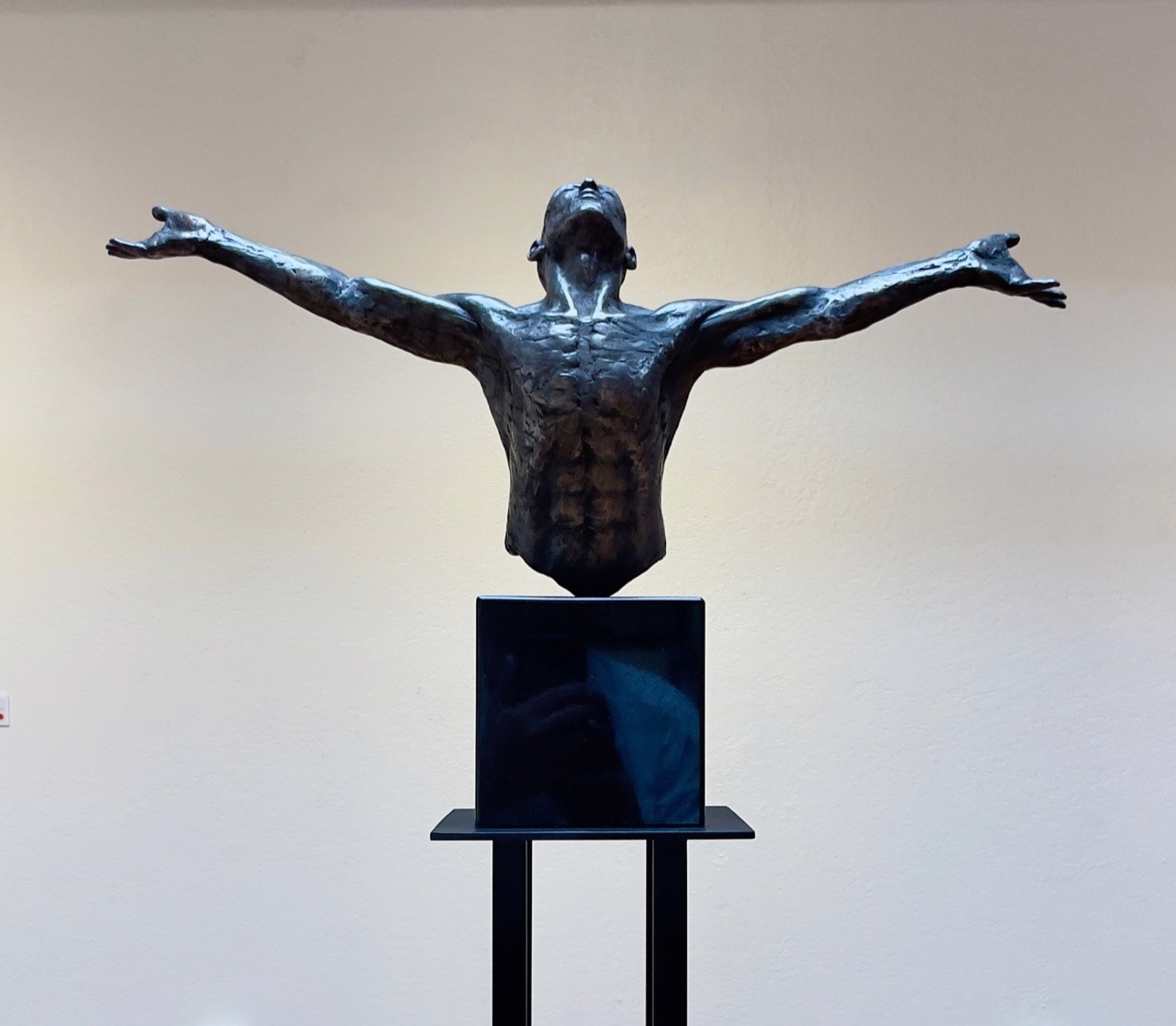 A bronze sculpture of a man with his arms outstretched.