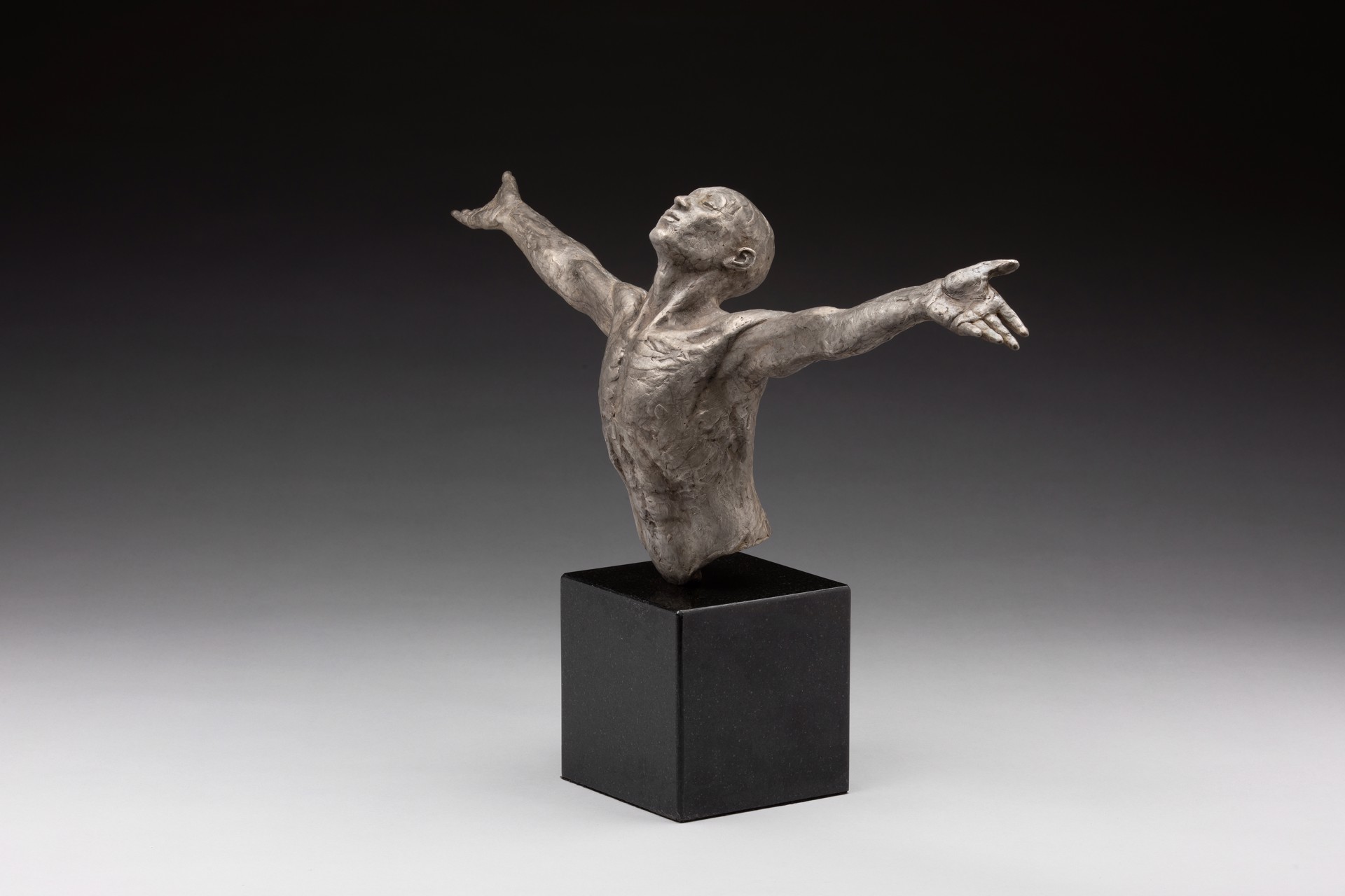 A bronze sculpture of a man with his arms outstretched.