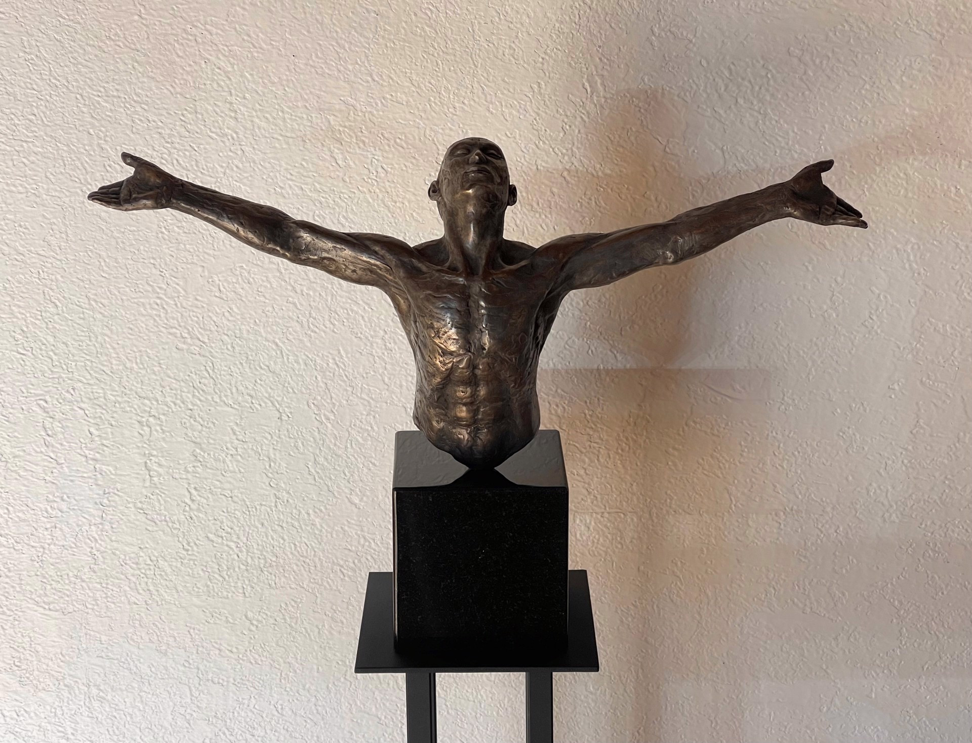 A bronze sculpture of a man with his arms outstretched.