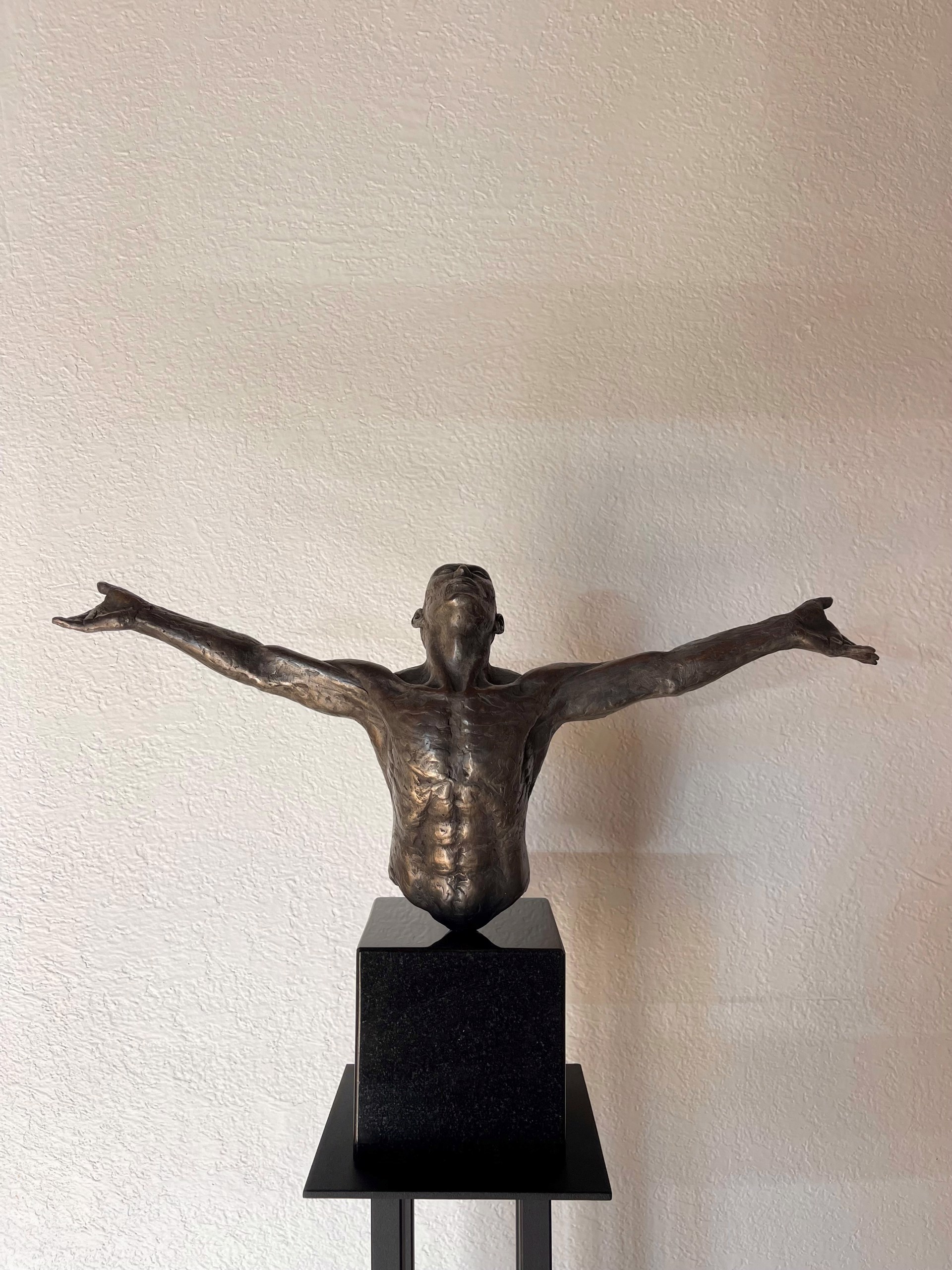 A bronze sculpture of a man with his arms outstretched.