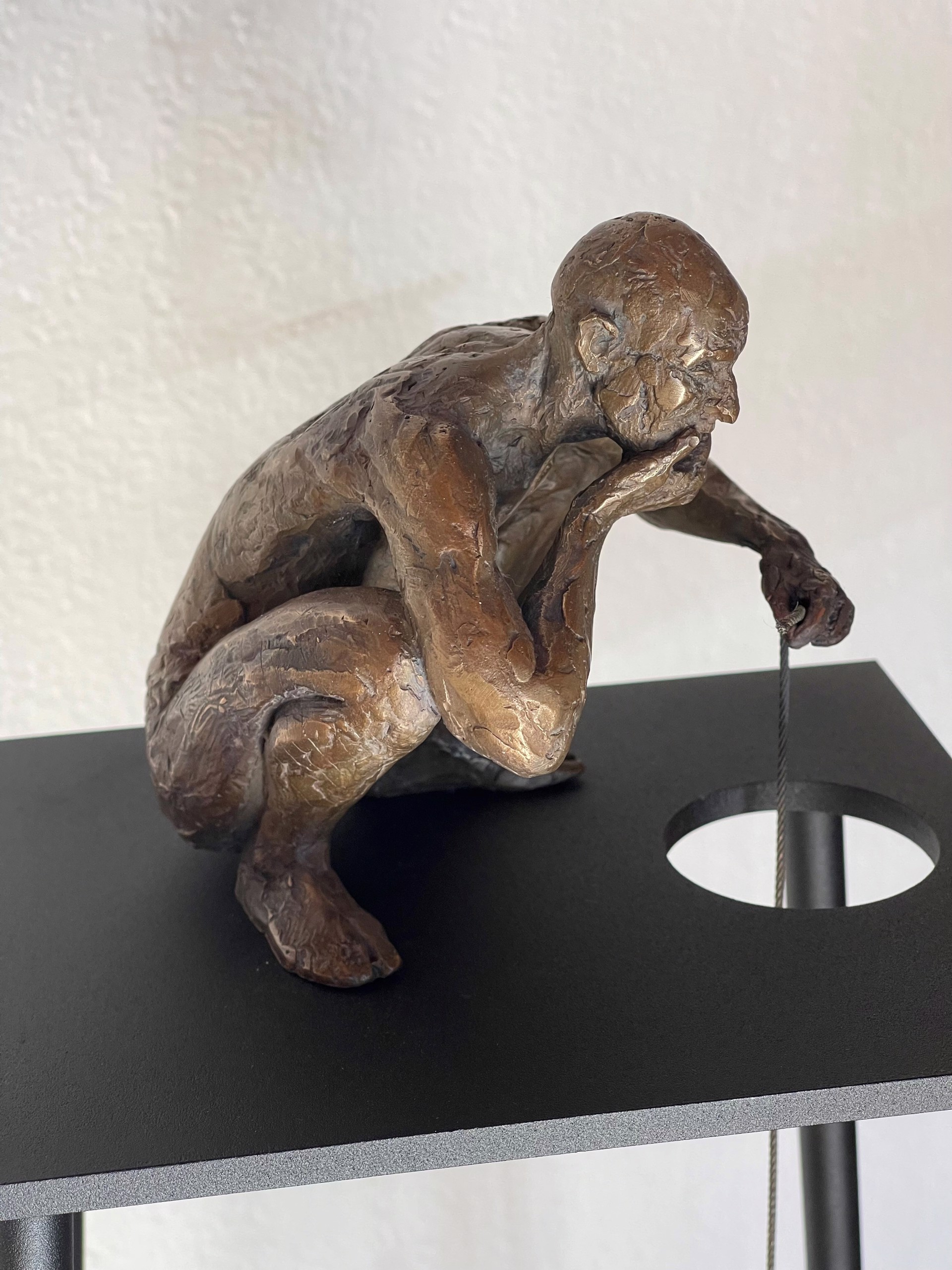 A bronze sculpture of a man sitting on top of a table.