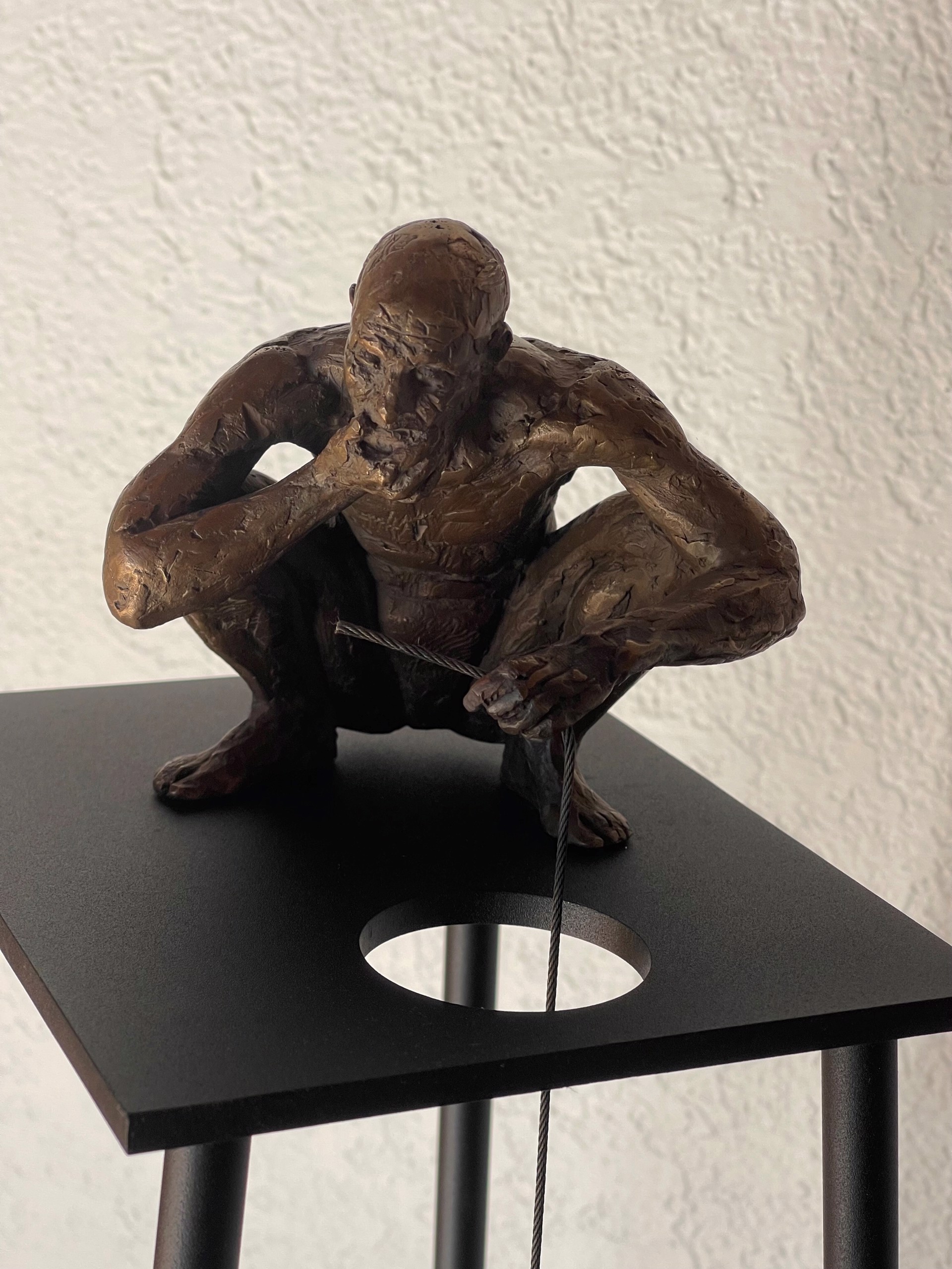 A bronze sculpture of a man sitting on top of a table.