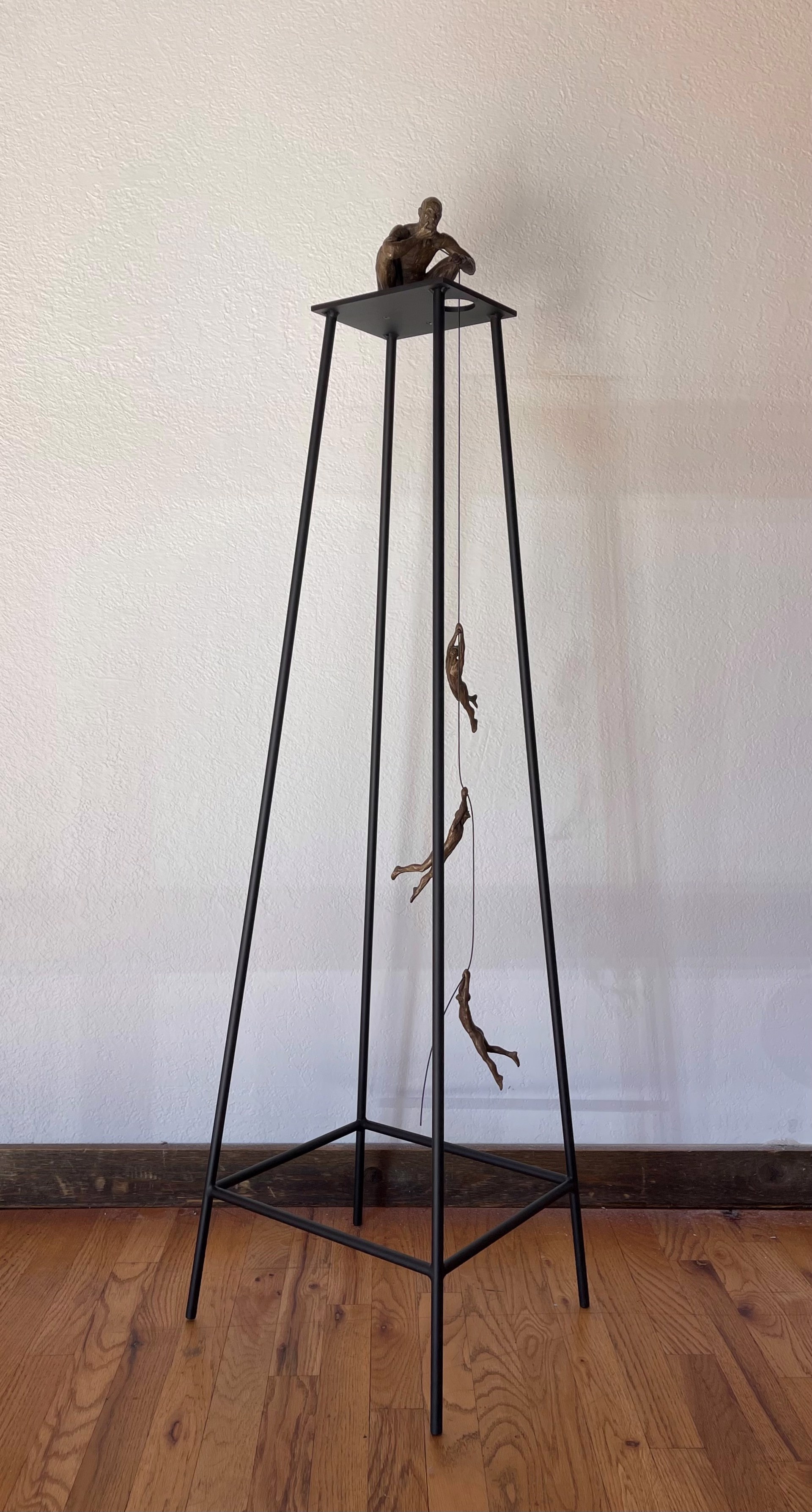 A bronze sculpture of a man sitting on top of a table.