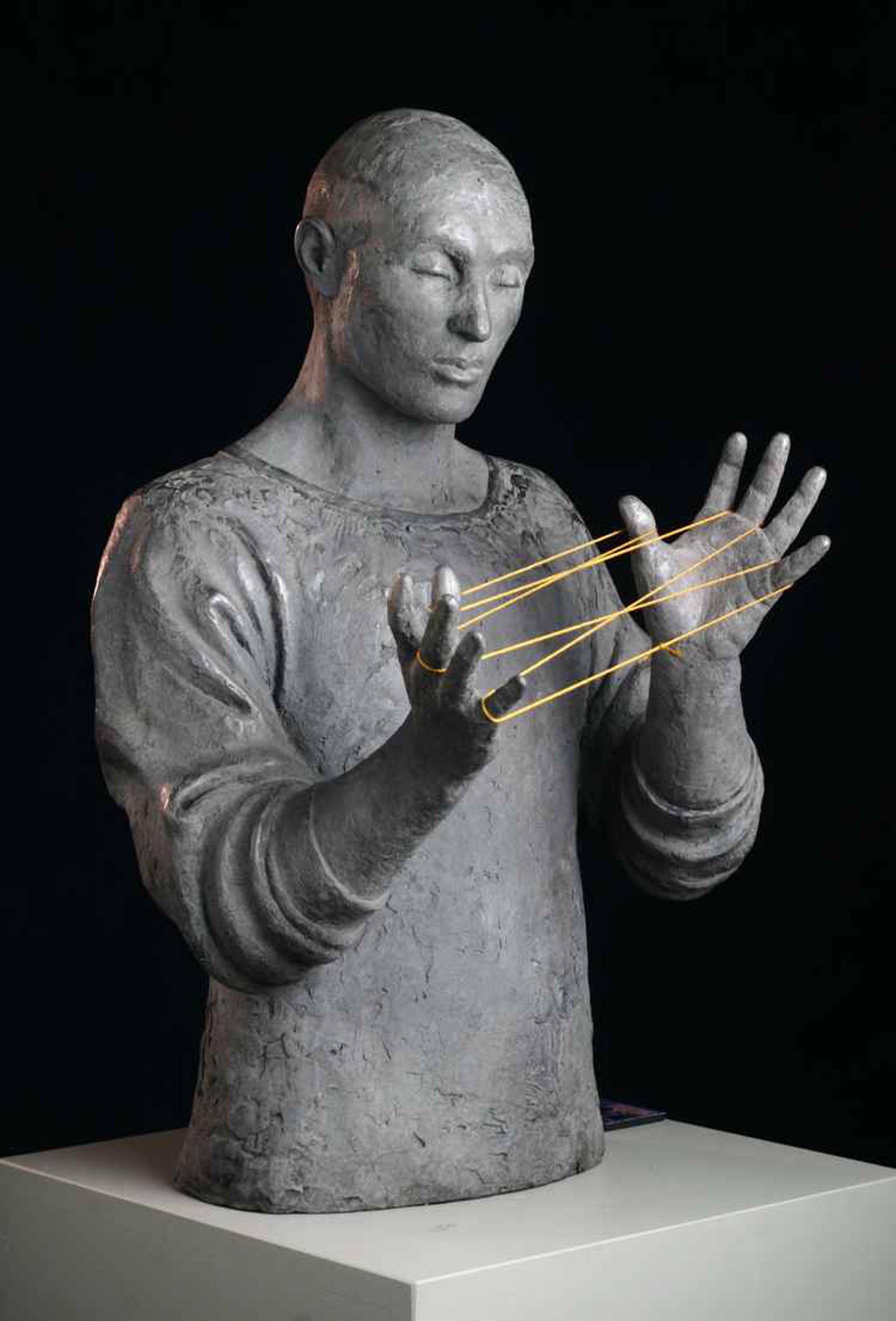 A grey bust of a figure holding yellow rubber bands between their hands.
