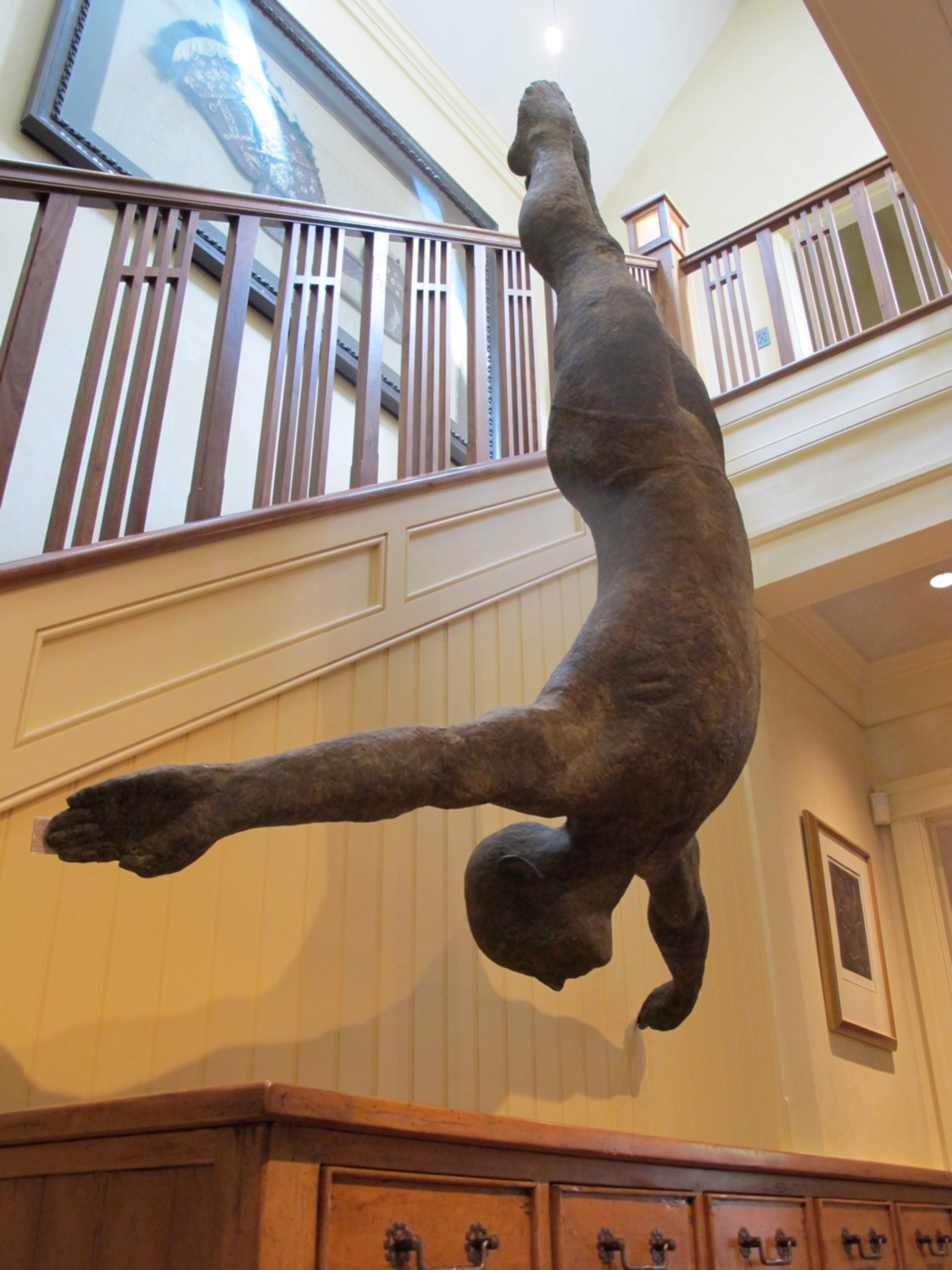 Two bronze figures appear to be floating or diving in mid-air against a stone wall.