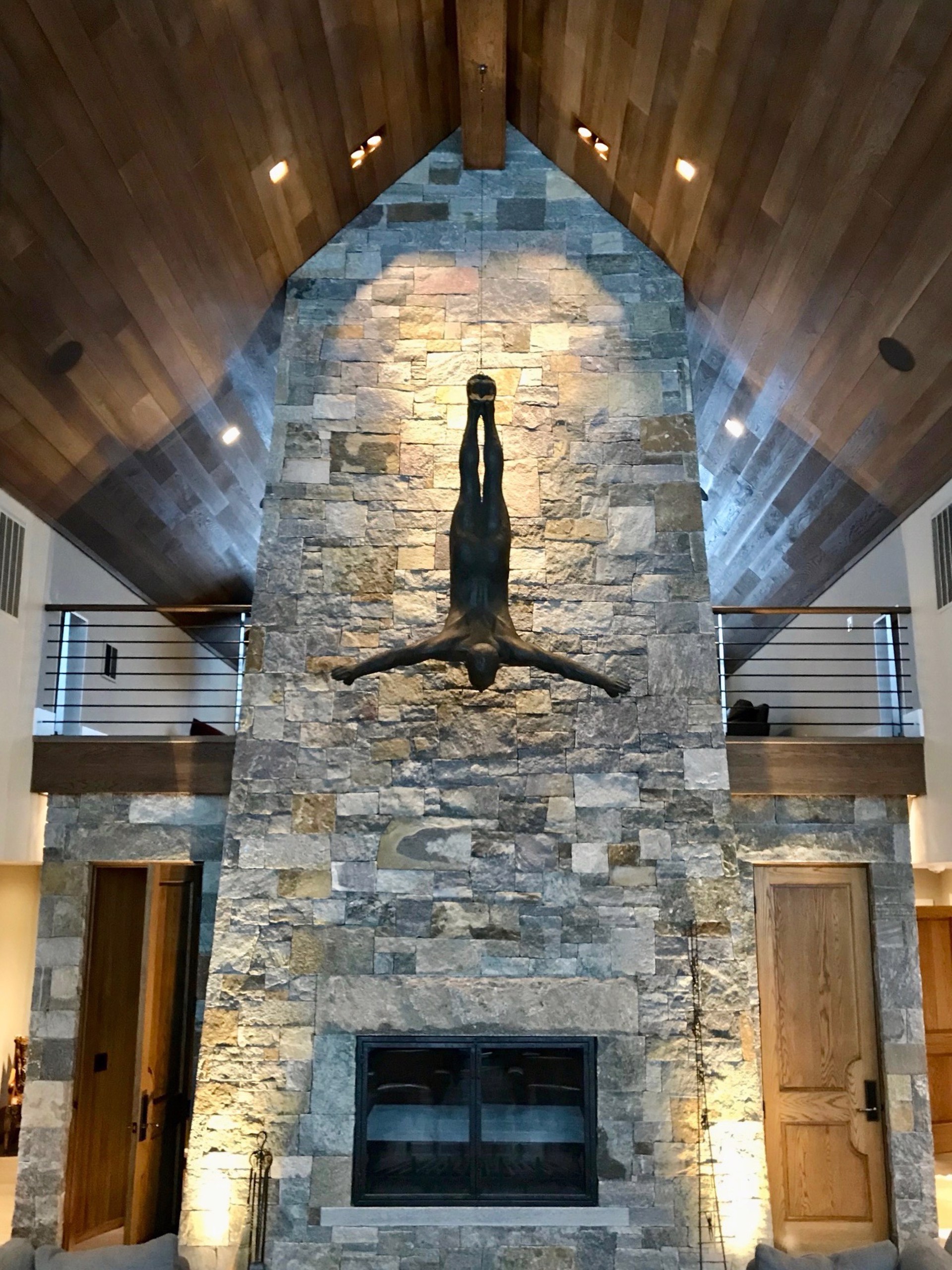 Two bronze figures appear to be floating or diving in mid-air against a stone wall.