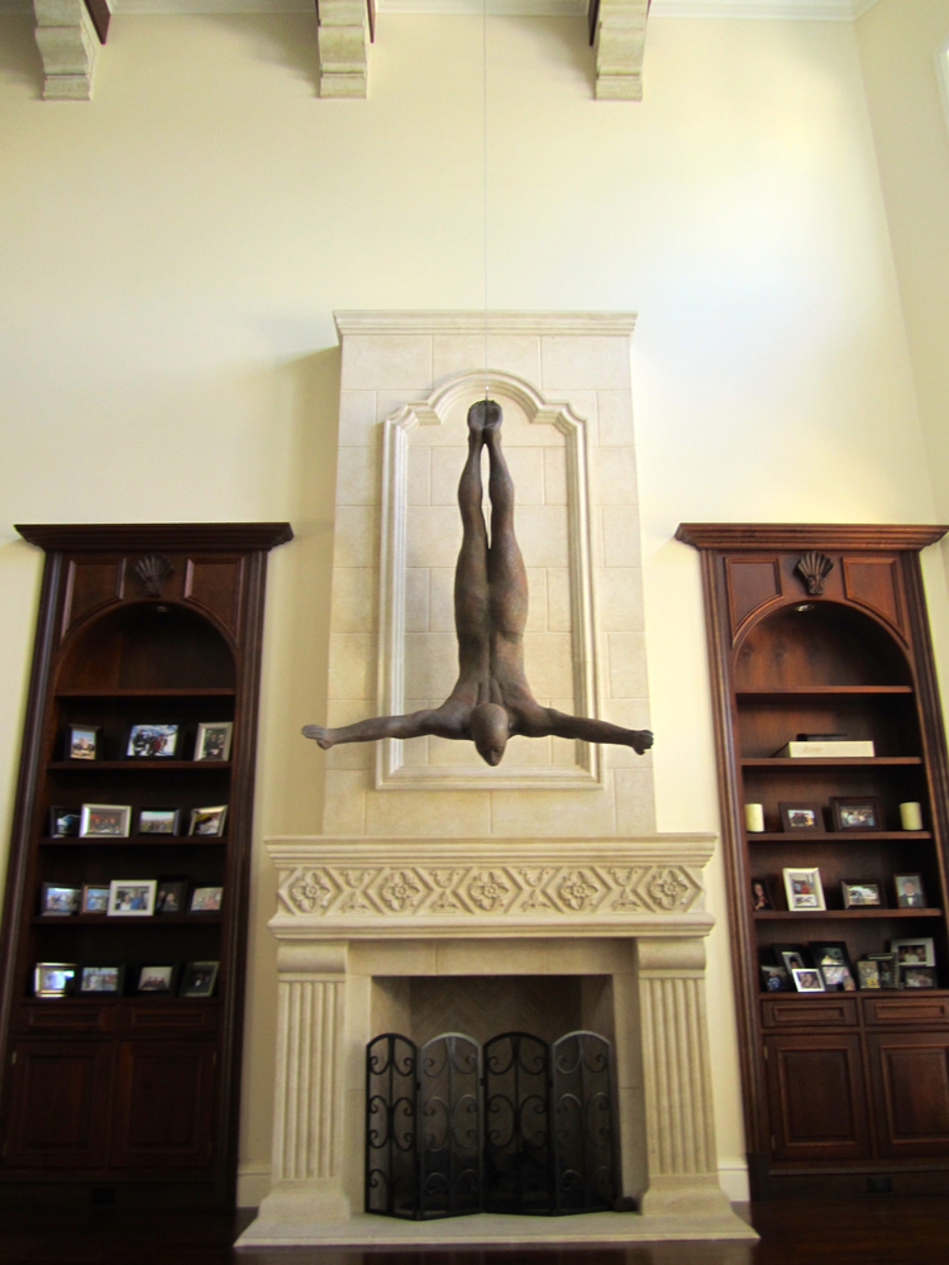 Two bronze figures appear to be floating or diving in mid-air against a stone wall.