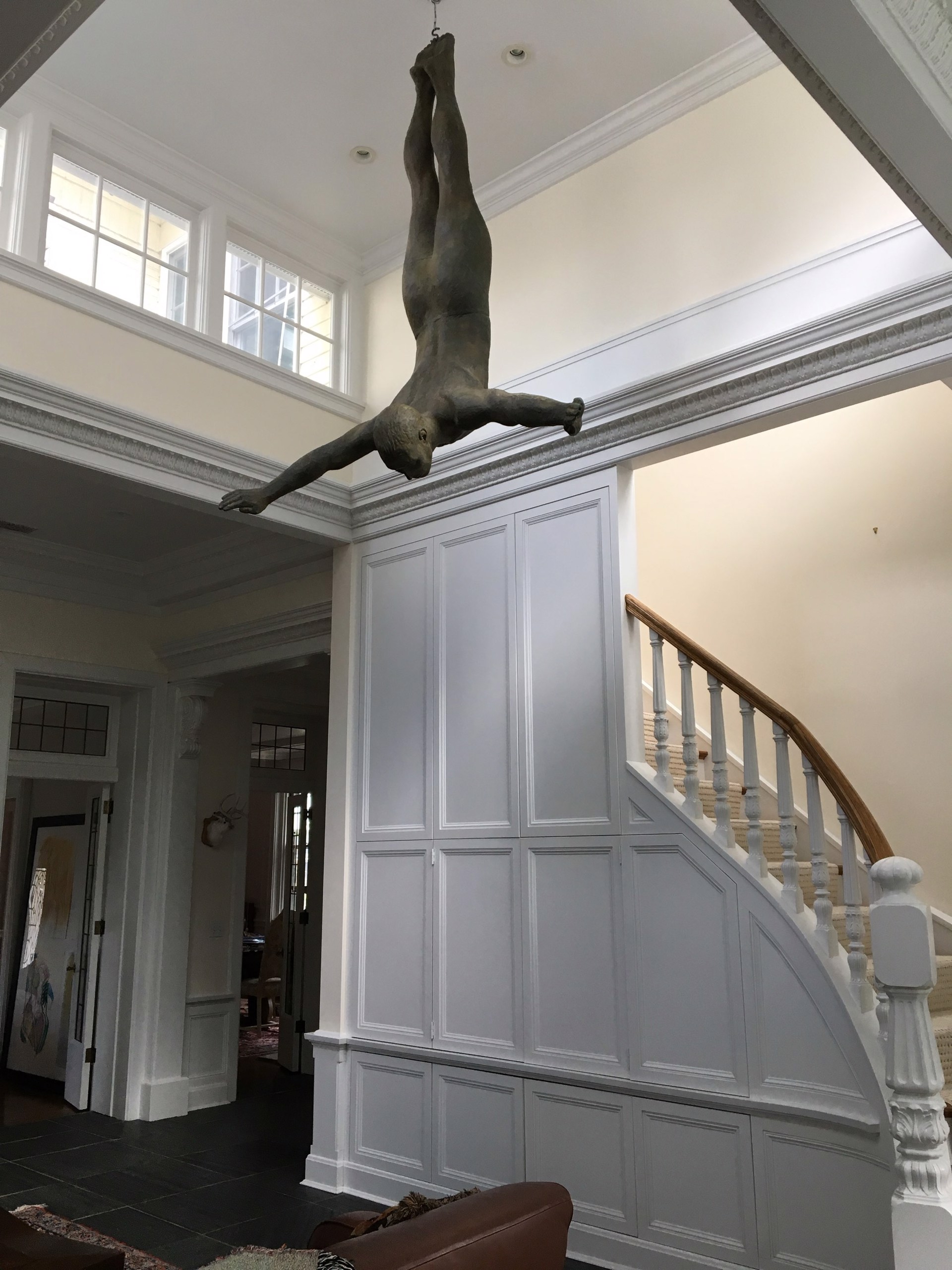 Two bronze figures appear to be floating or diving in mid-air against a stone wall.