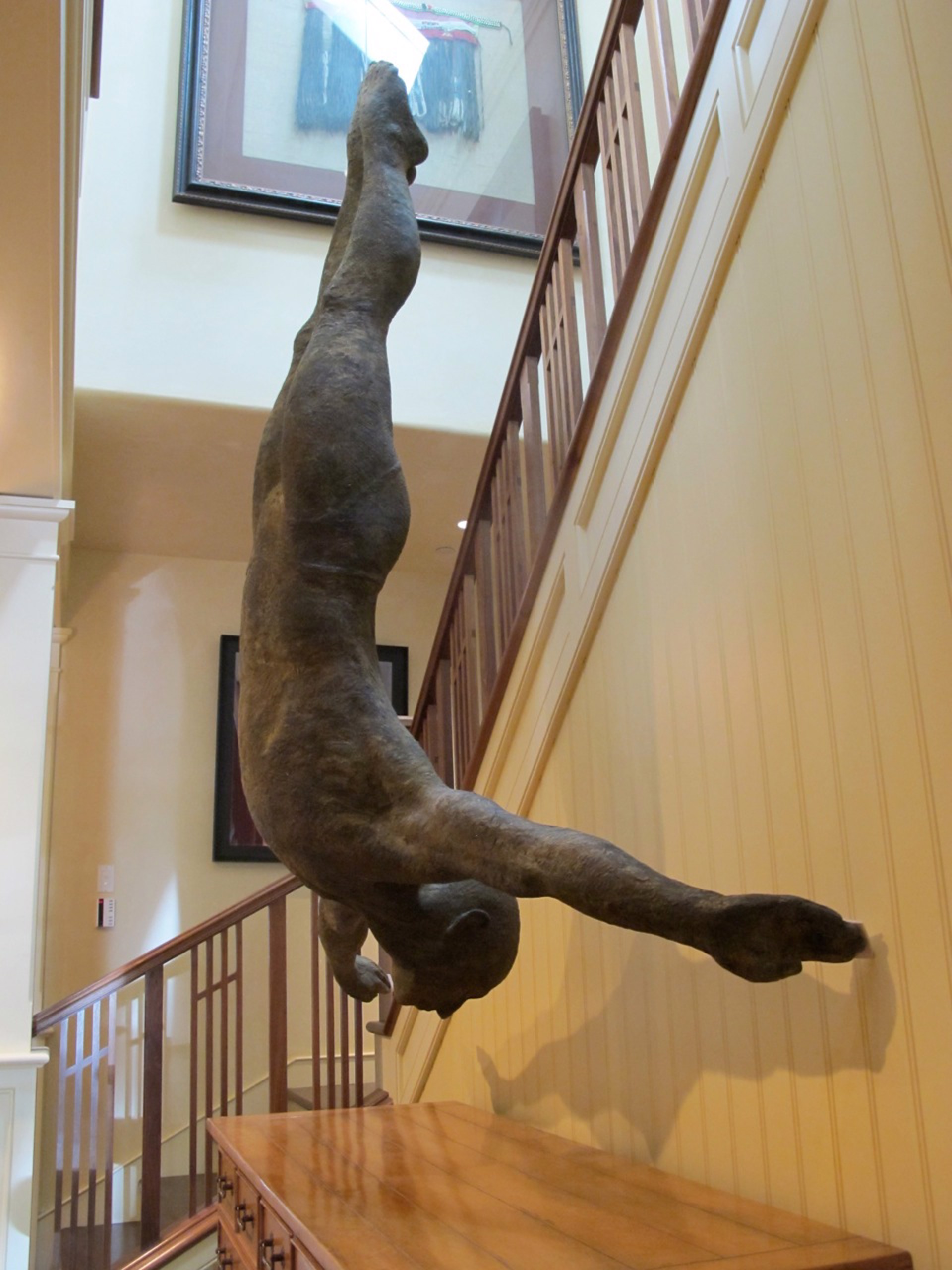 Two bronze figures appear to be floating or diving in mid-air against a stone wall.