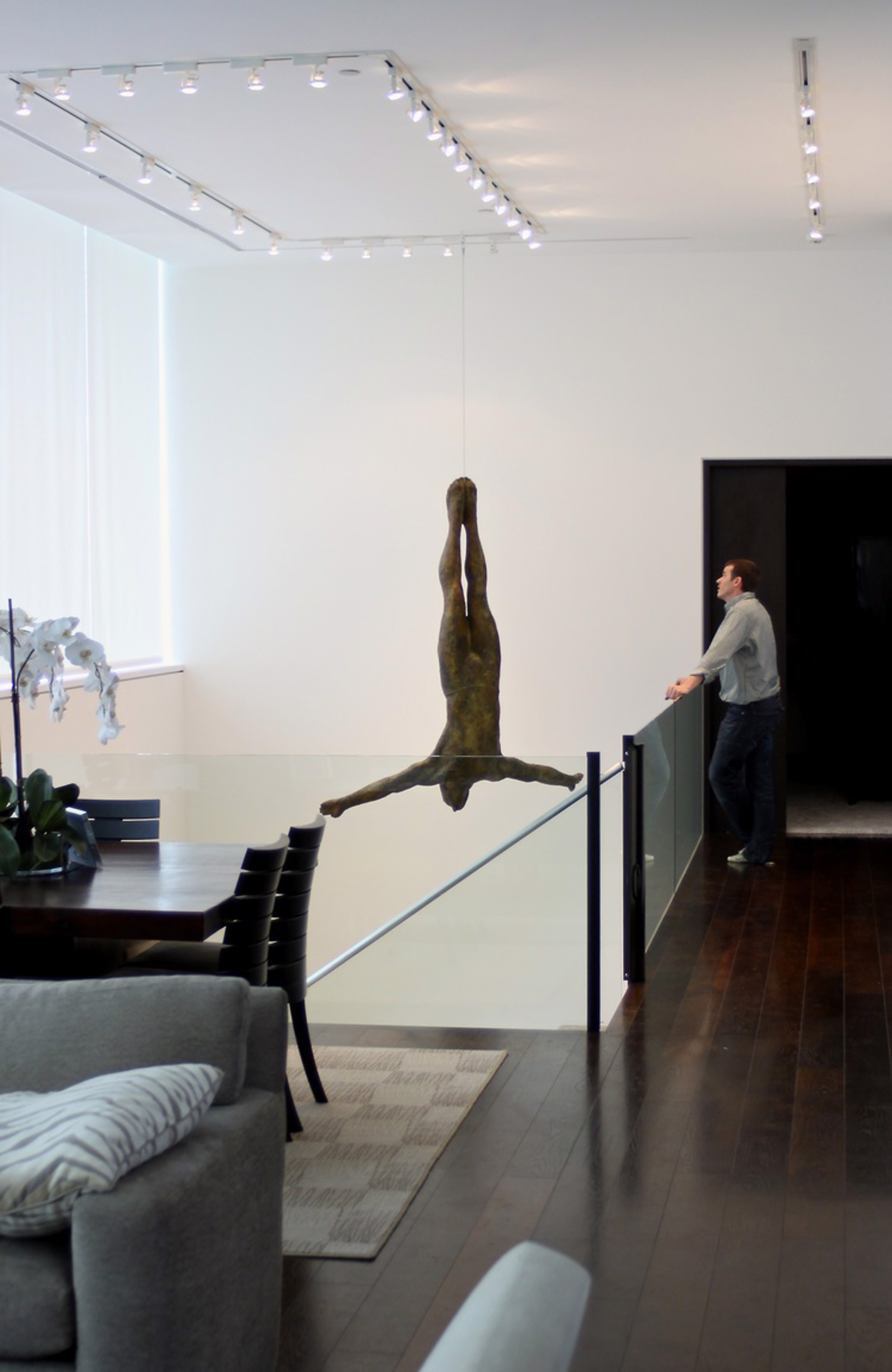 Two bronze figures appear to be floating or diving in mid-air against a stone wall.