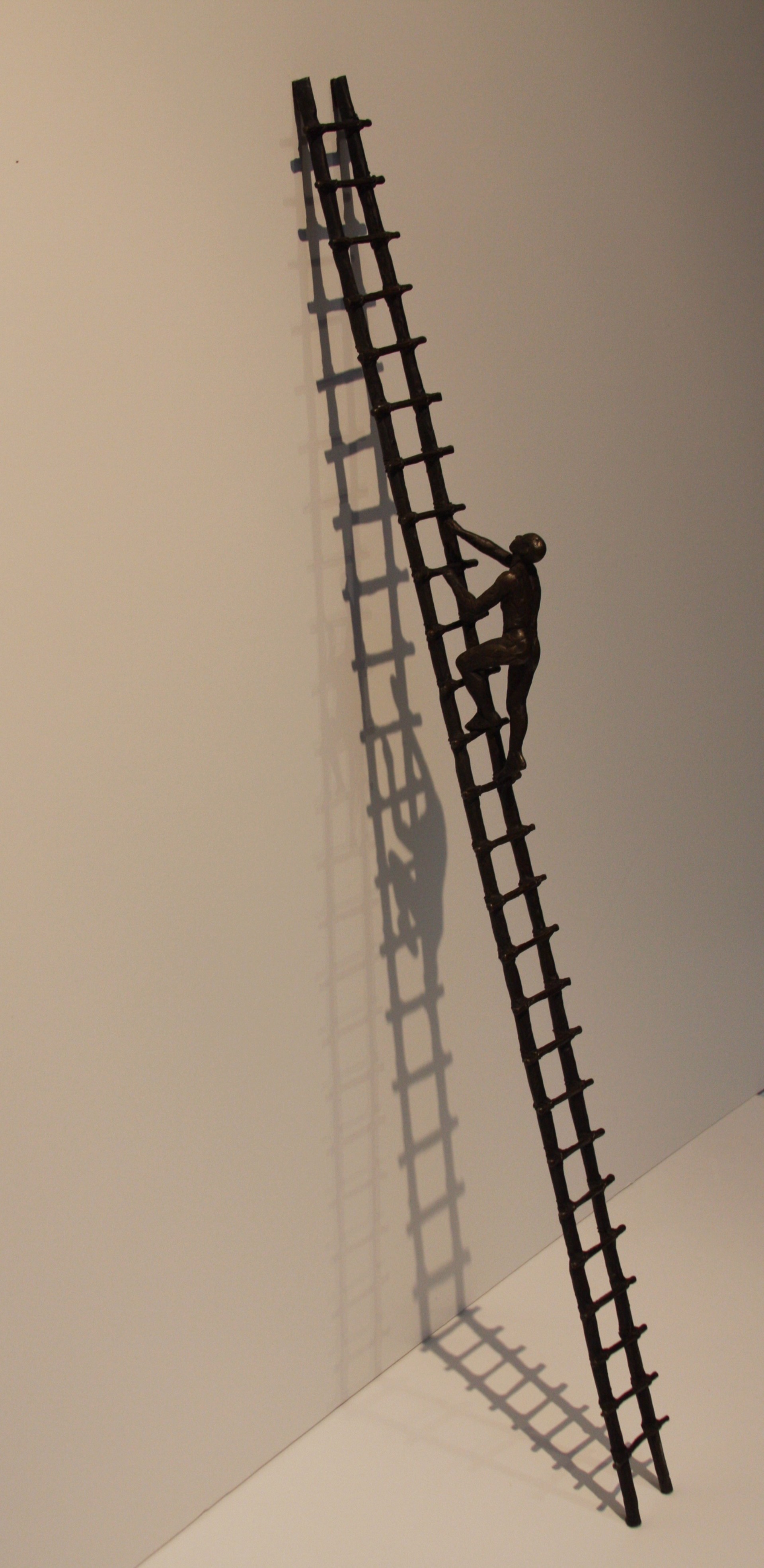 A metal sculpture of a man climbing a ladder.