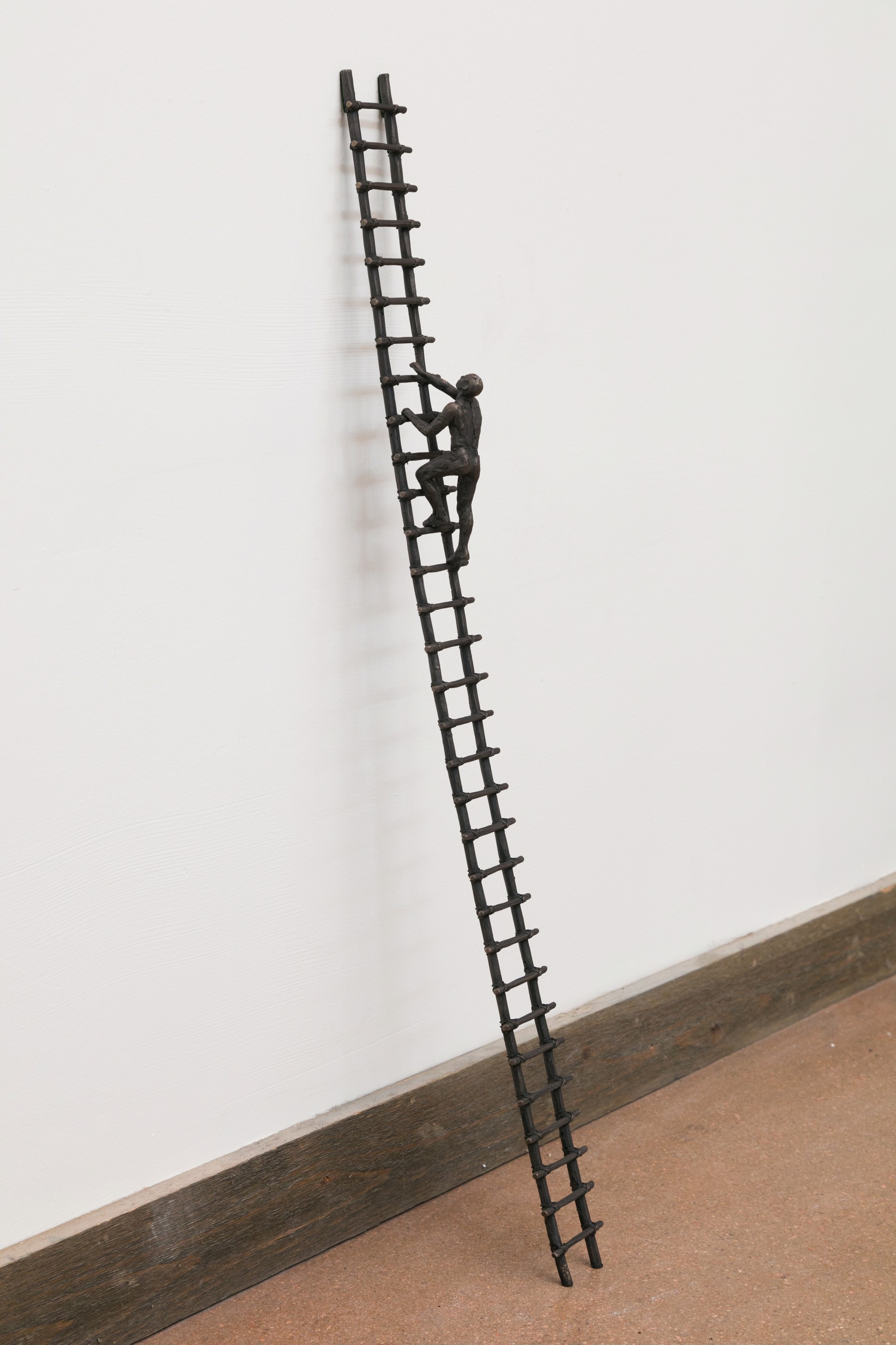 A metal sculpture of a man climbing a ladder.