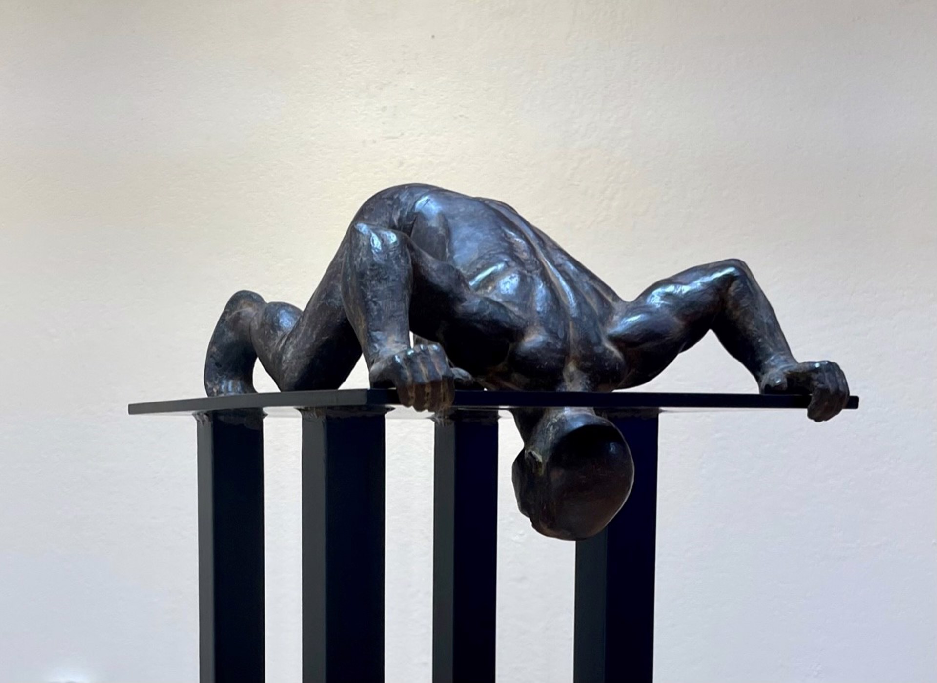 A bronze sculpture of a woman laying on a pedestal.