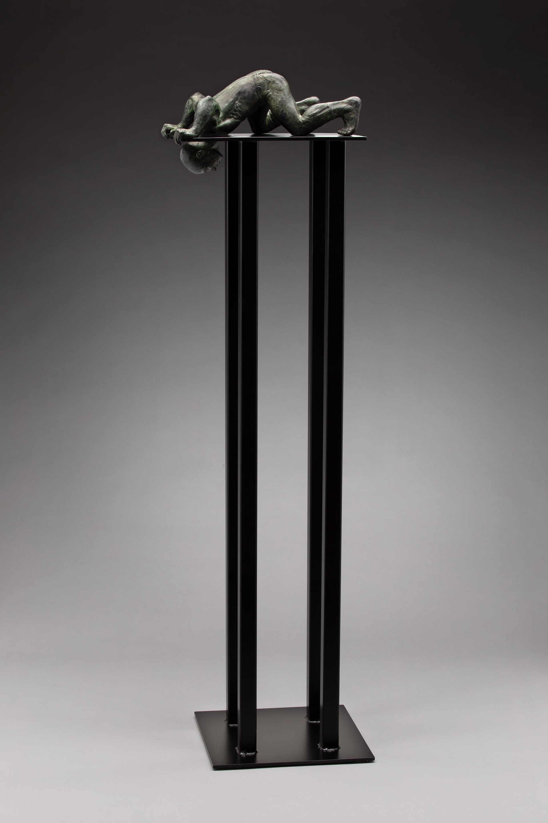 A bronze sculpture of a woman laying on a pedestal.