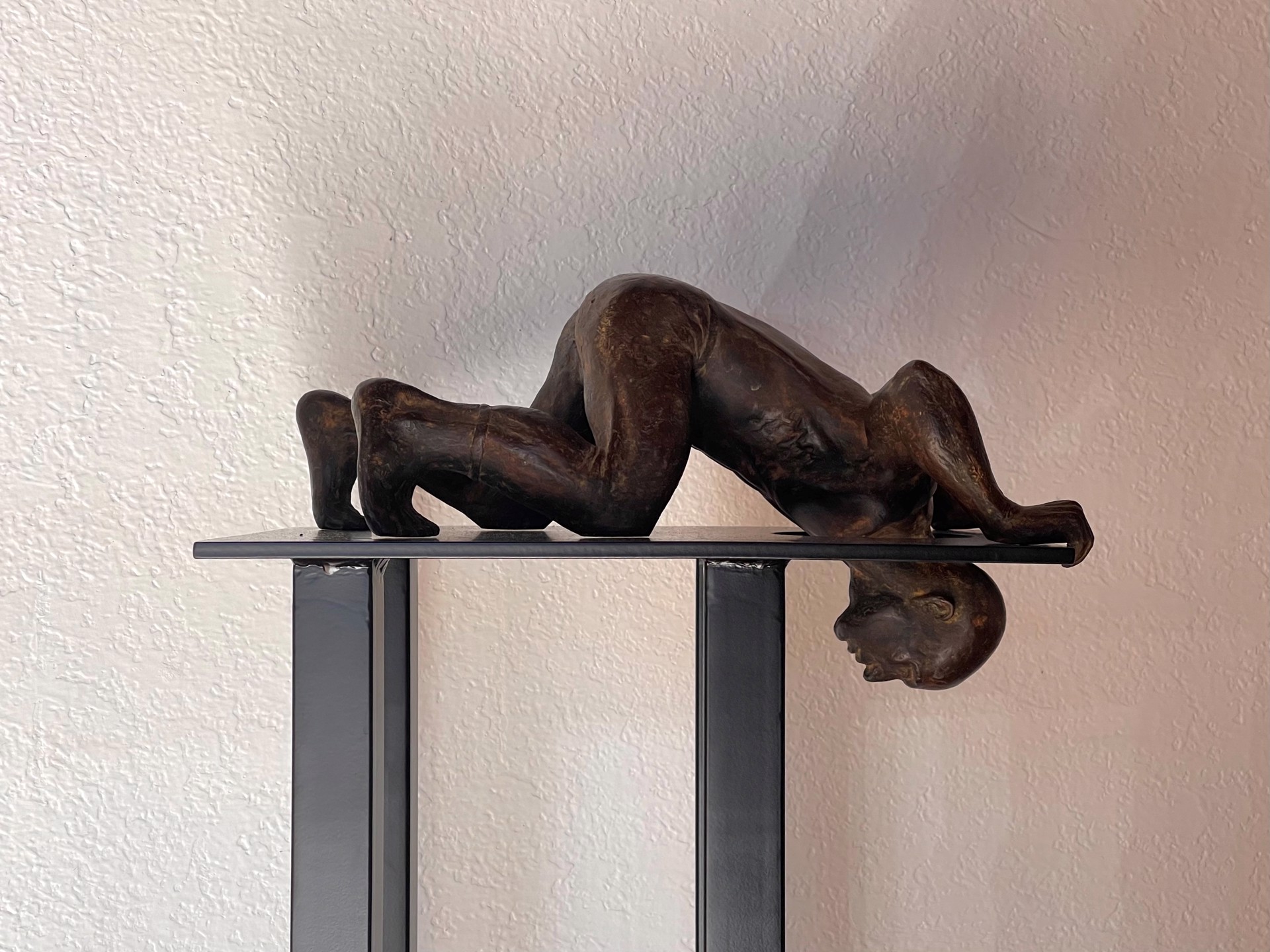 A bronze sculpture of a woman laying on a pedestal.