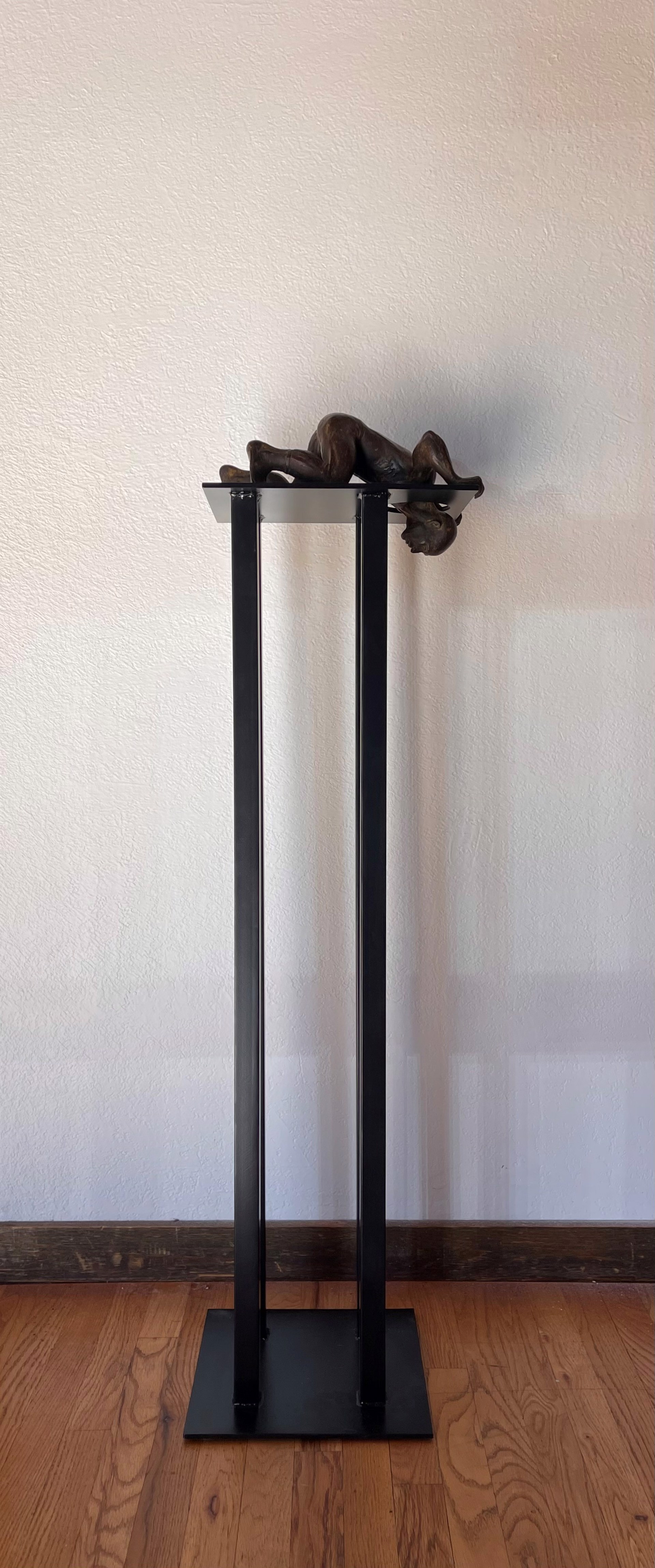 A bronze sculpture of a woman laying on a pedestal.