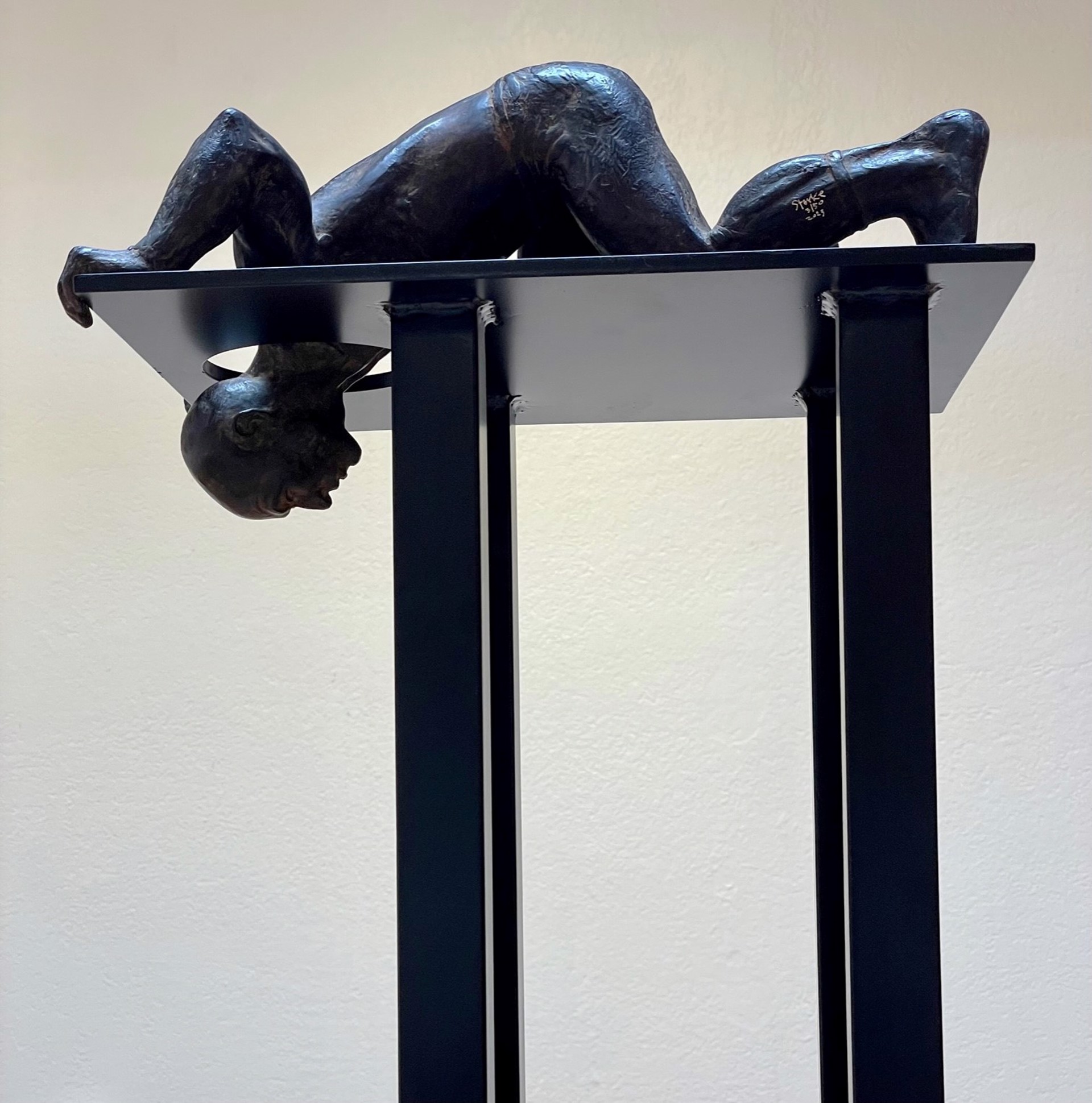 A bronze sculpture of a woman laying on a pedestal.