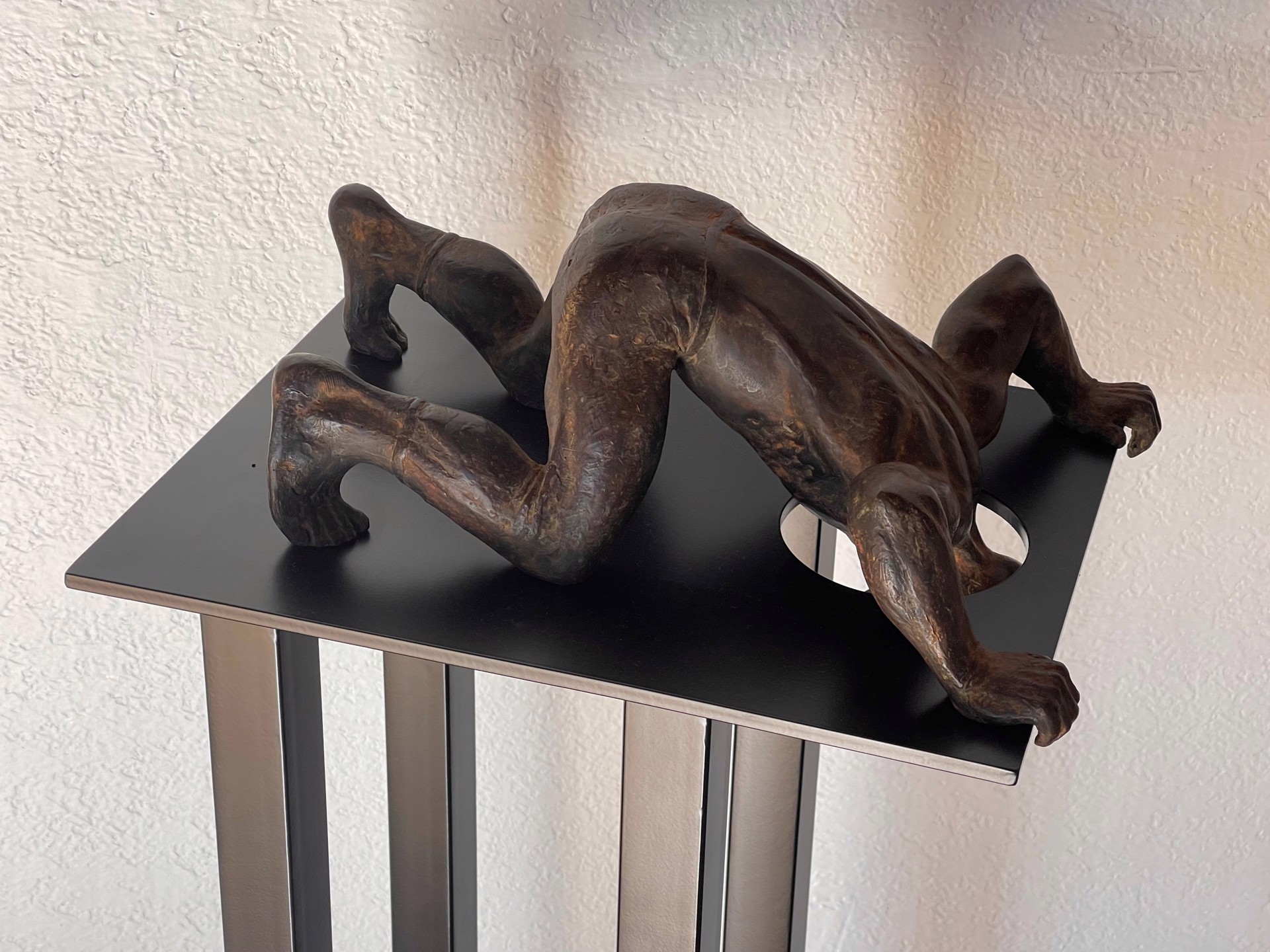 A bronze sculpture of a woman laying on a pedestal.