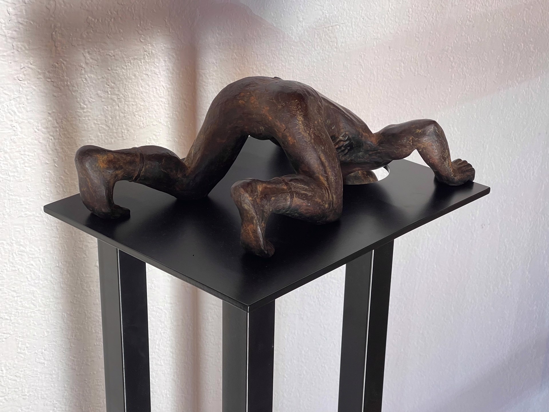 A bronze sculpture of a woman laying on a pedestal.